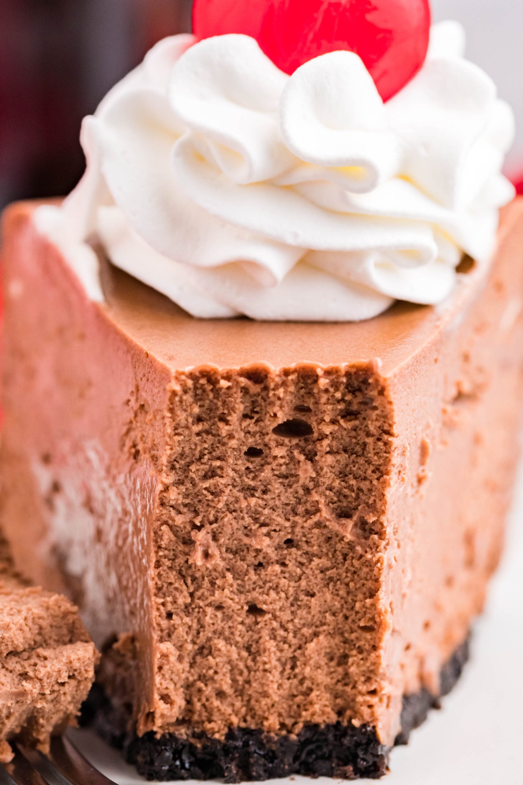 Front view of a slice of Coca Cola Cheesecake with a piece removed by a fork.