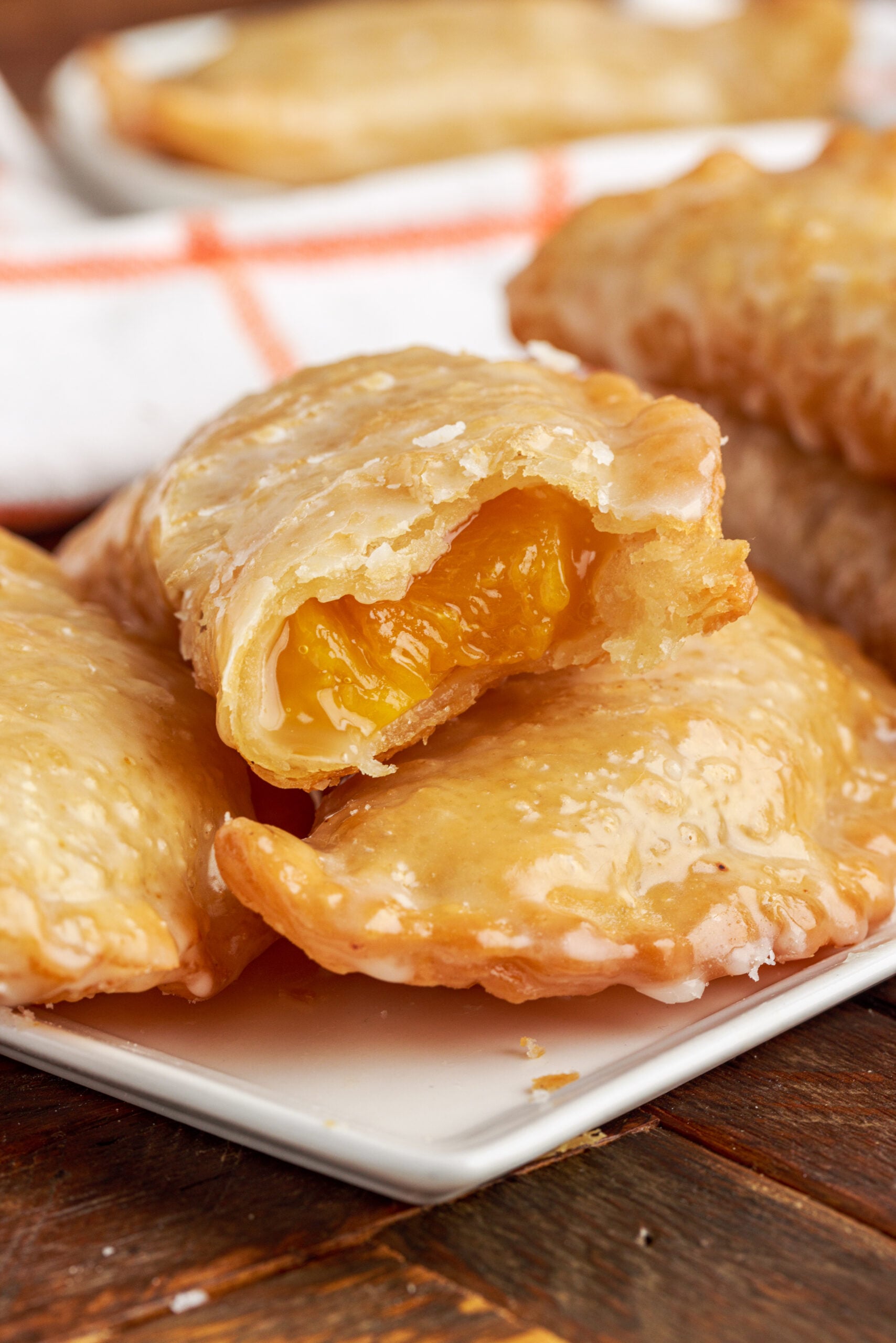 Up close view of two Peach Hand Pies stacked with a bite removed from the top pie.