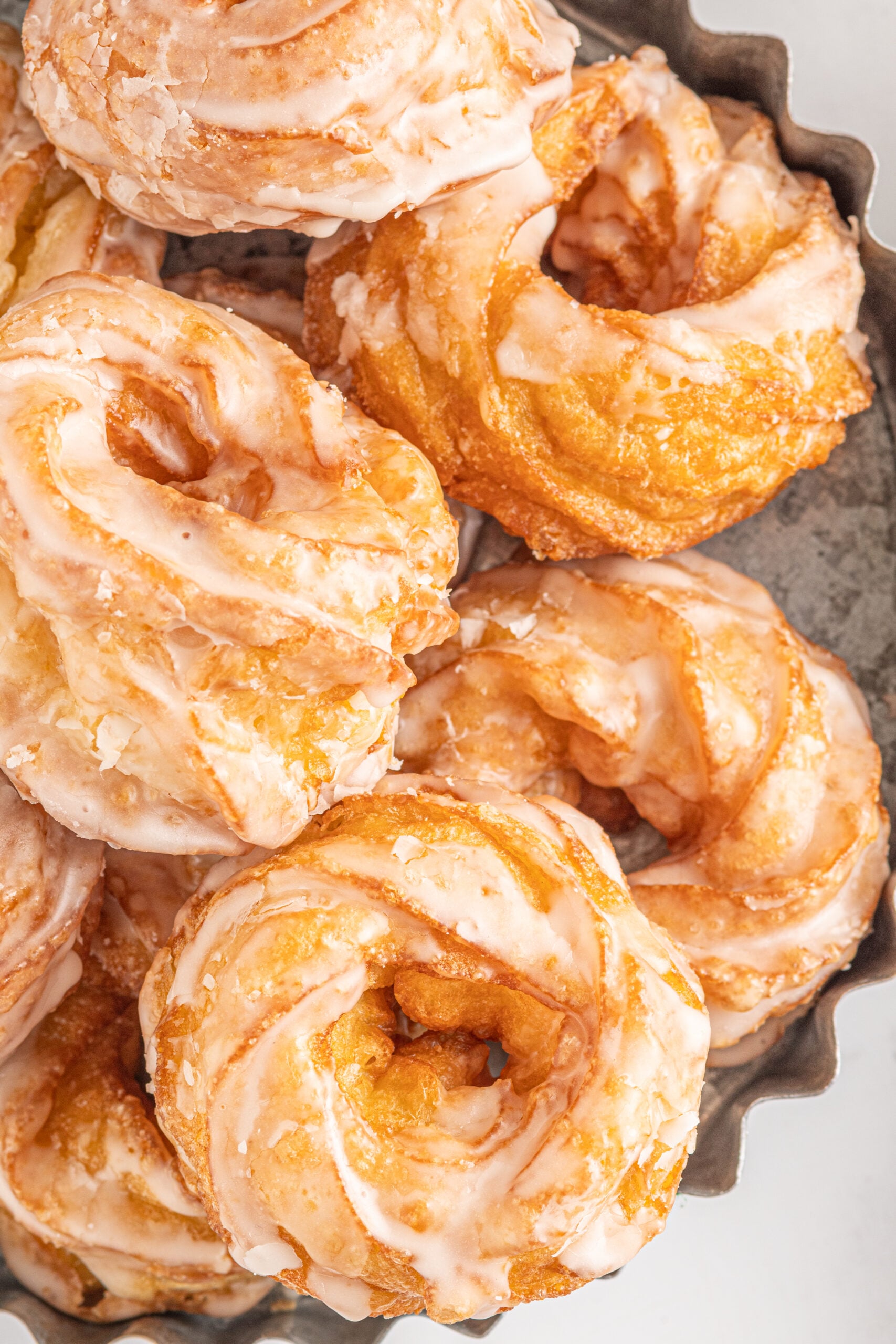 Up close view of French Crullers stacked on a silver serving tray.