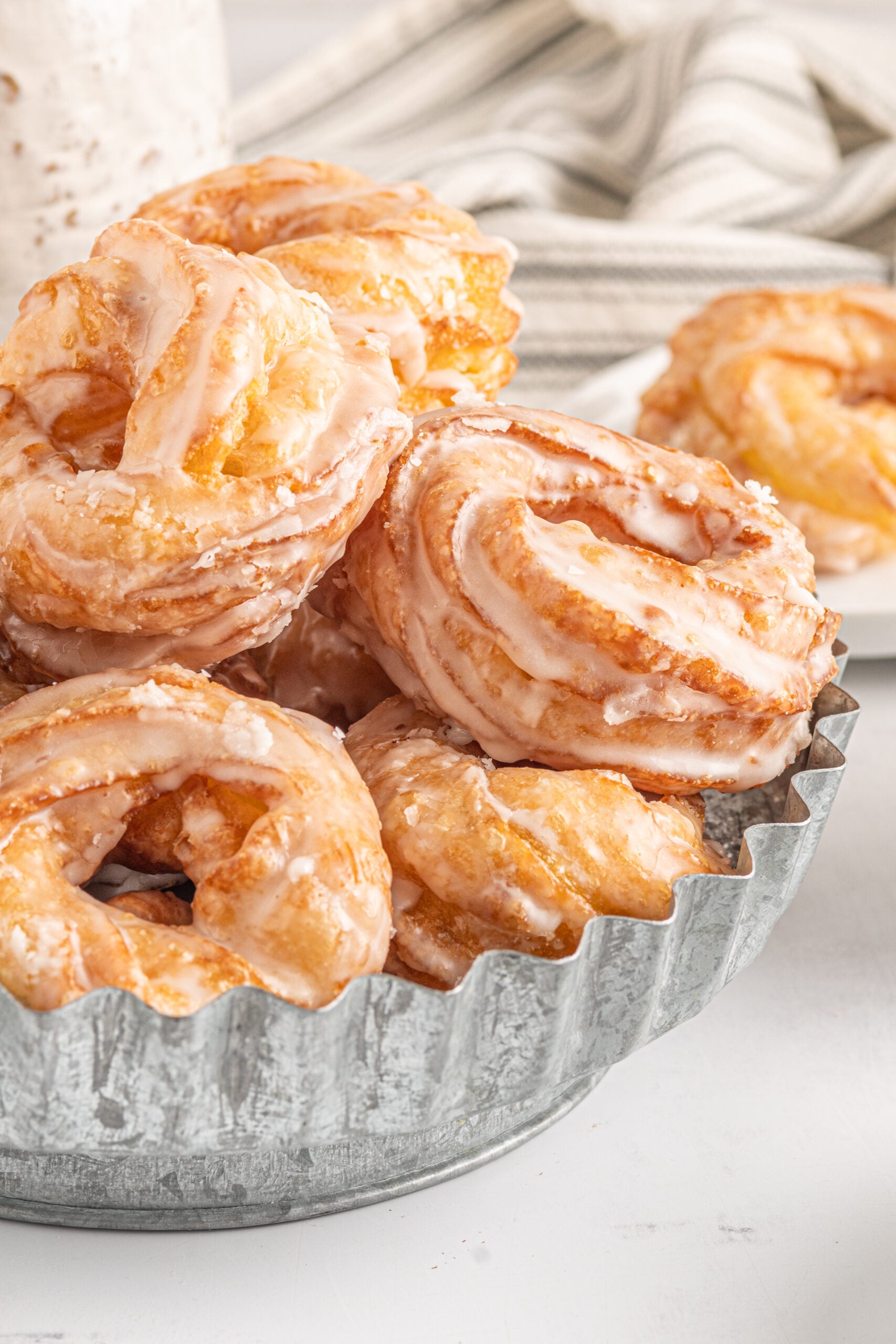 Up close view of French Crullers stacked on a silver serving tray.