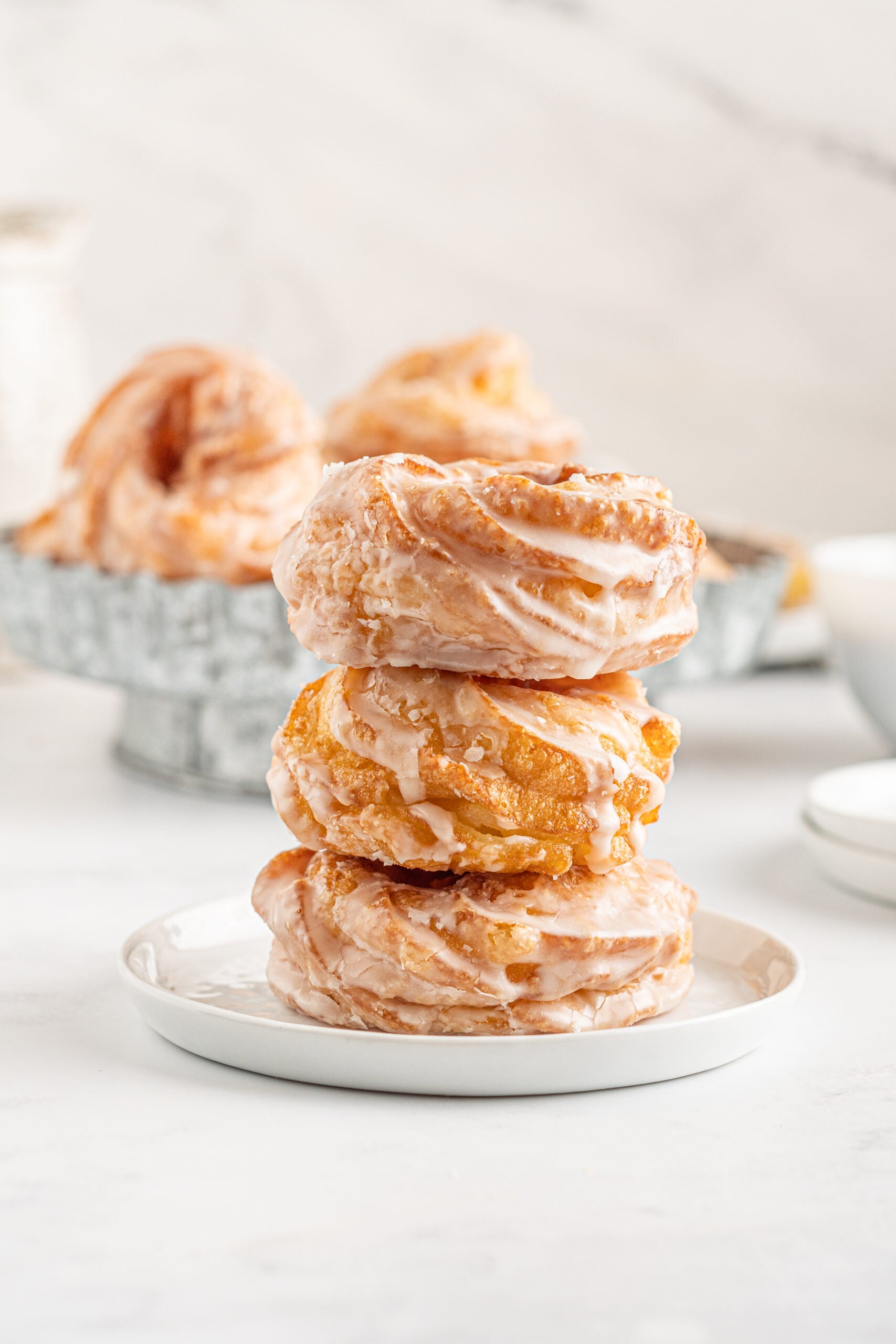 Front view of three French Crullers stacked on a white dish.