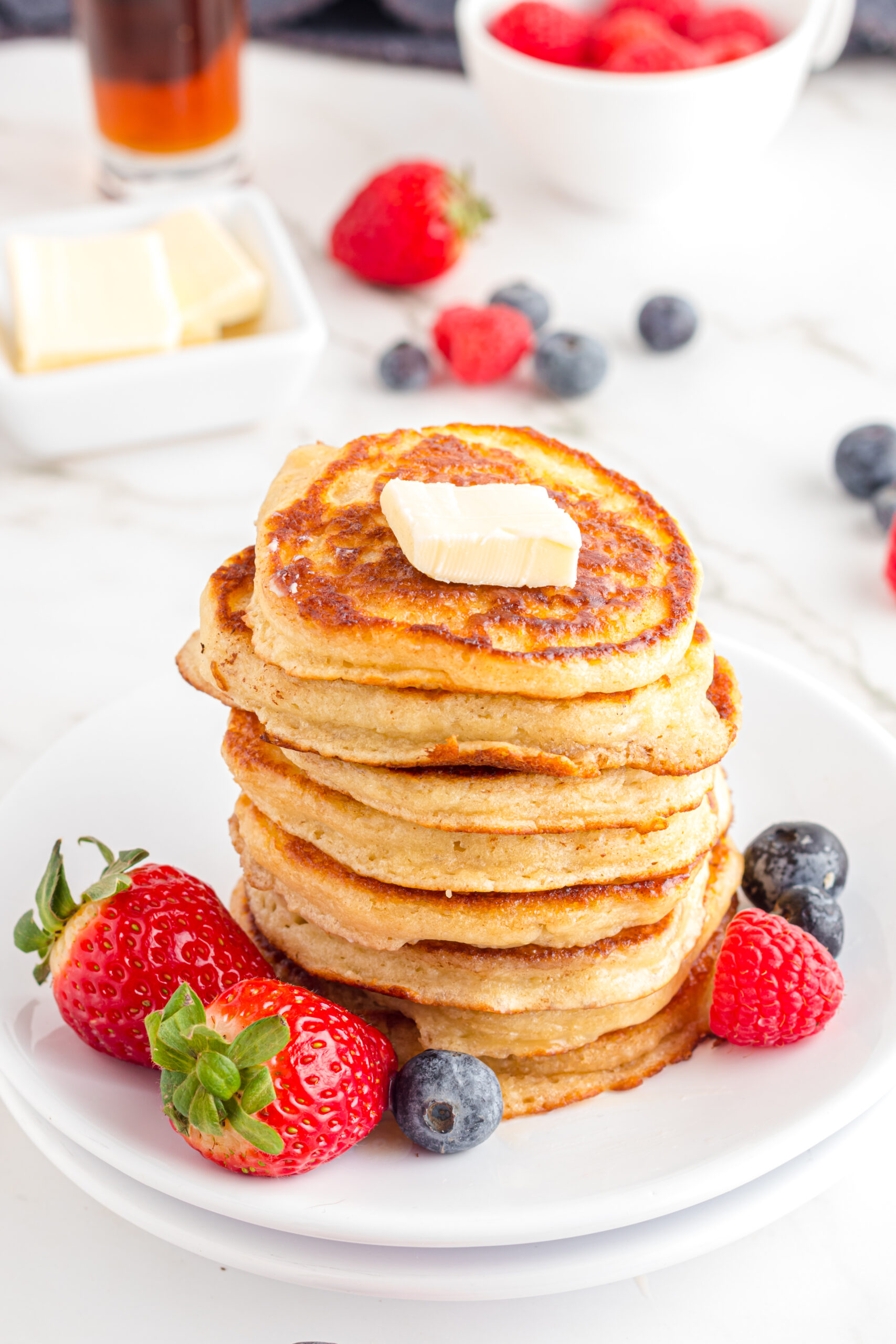 Front view of Mini Pancakes on a white dish served with strawberries and blueberries.