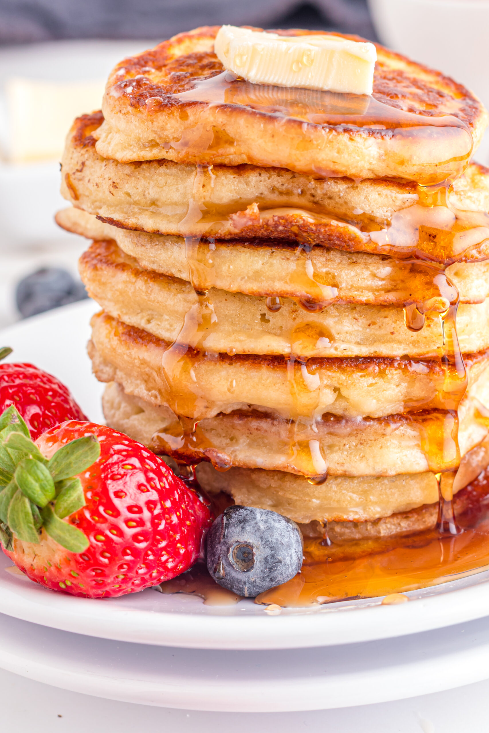 Front view of Mini Pancakes on a white dish served with strawberries and blueberries.