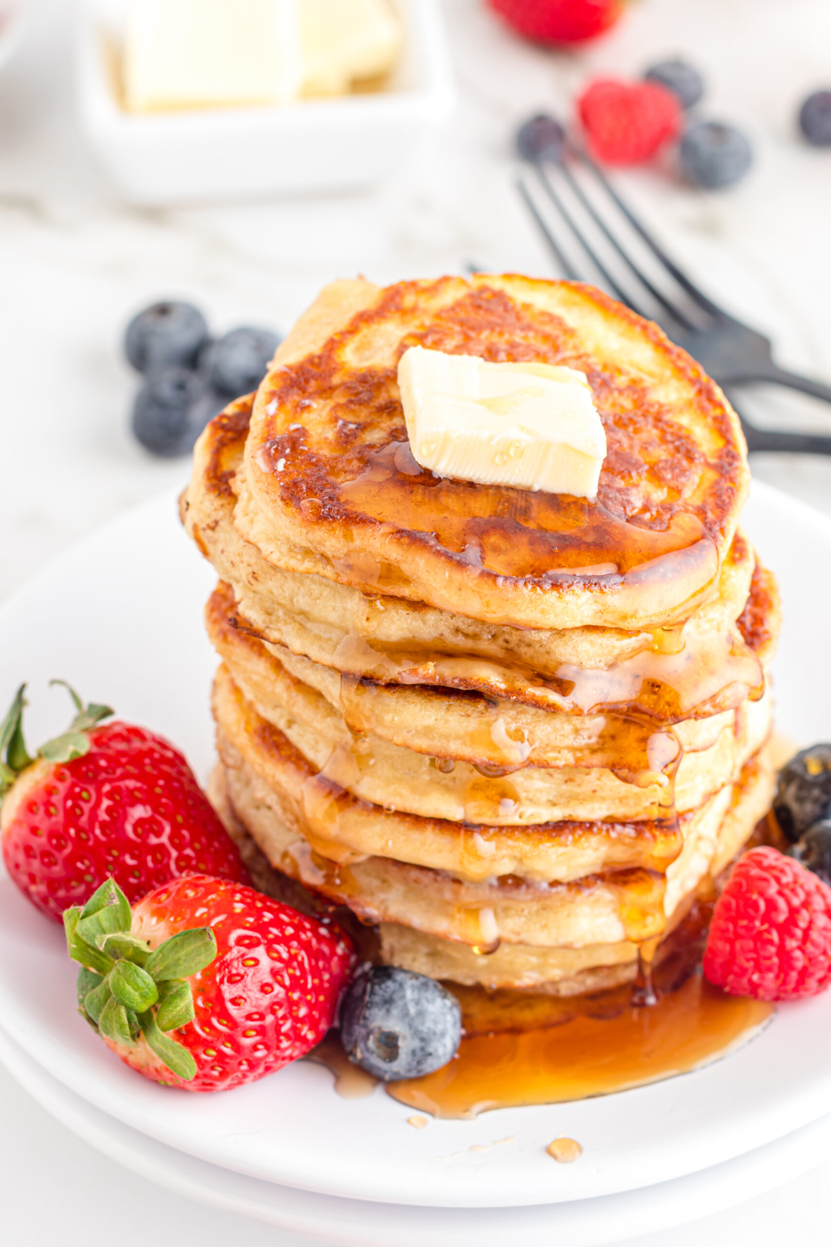 Front view of Mini Pancakes on a white dish served with strawberries and blueberries.