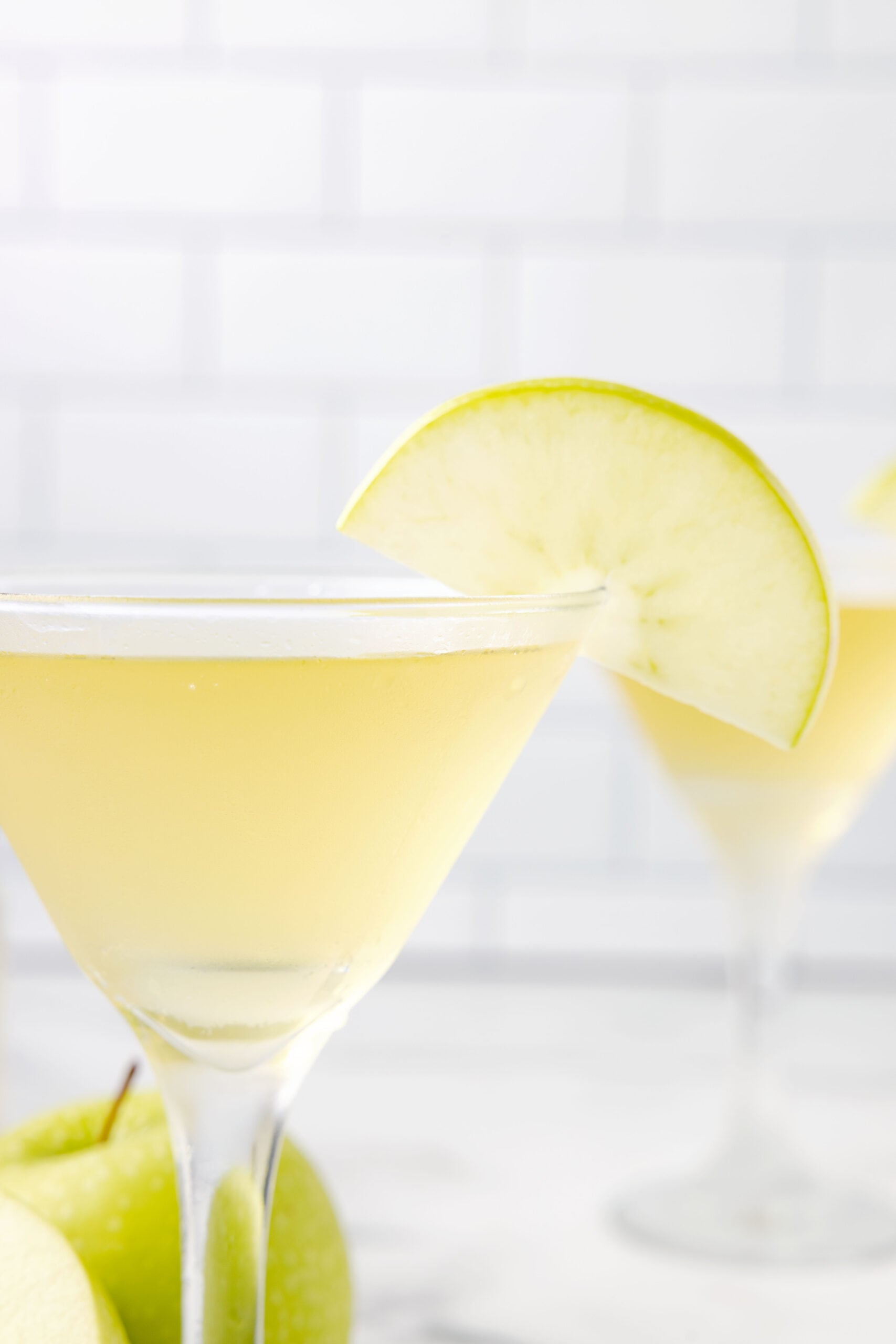 Close up view of appletinis in martini glasses garnished with sliced apples.