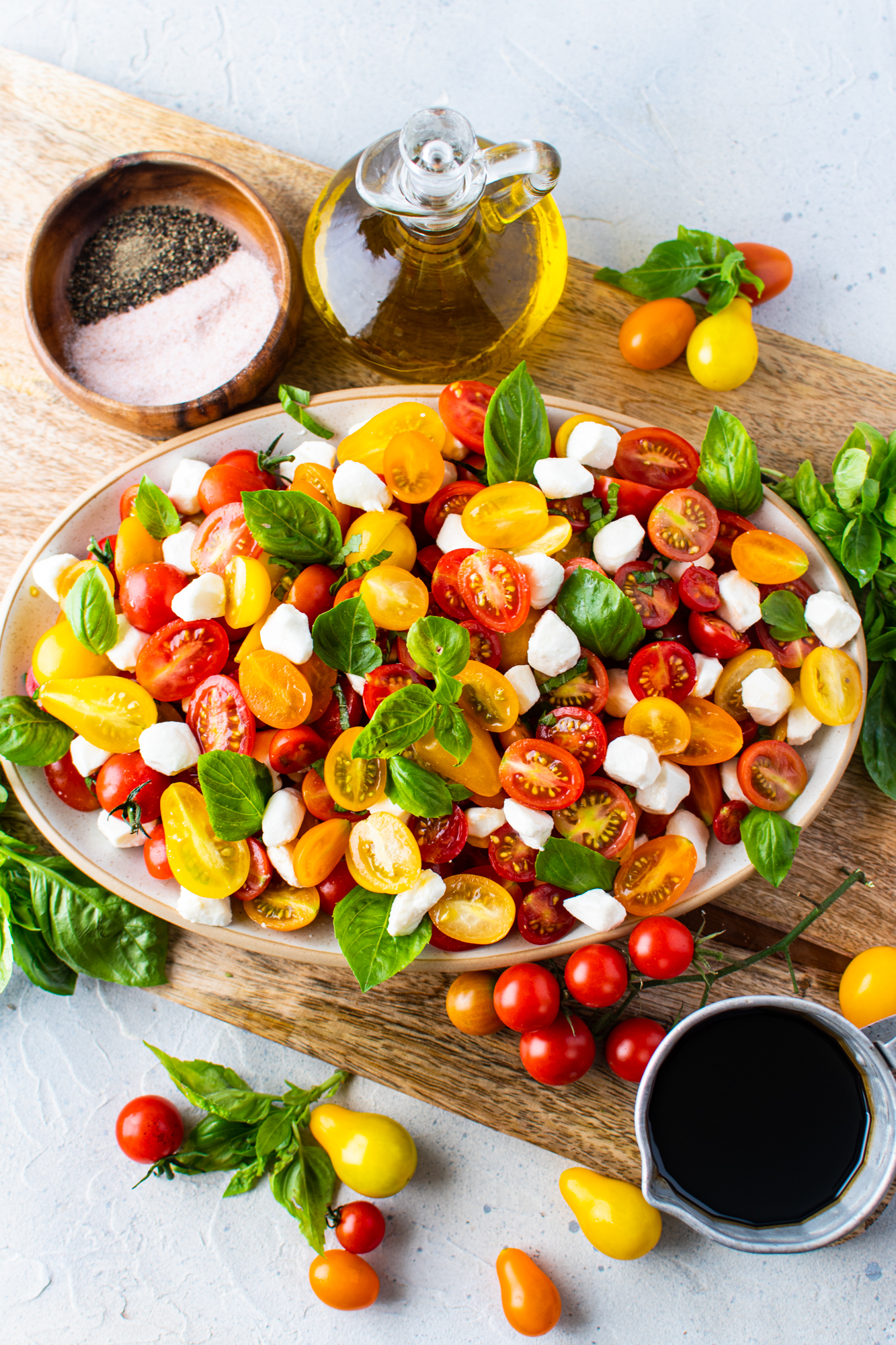 Overhead view of caprese salad on a white oval serving tray. 
