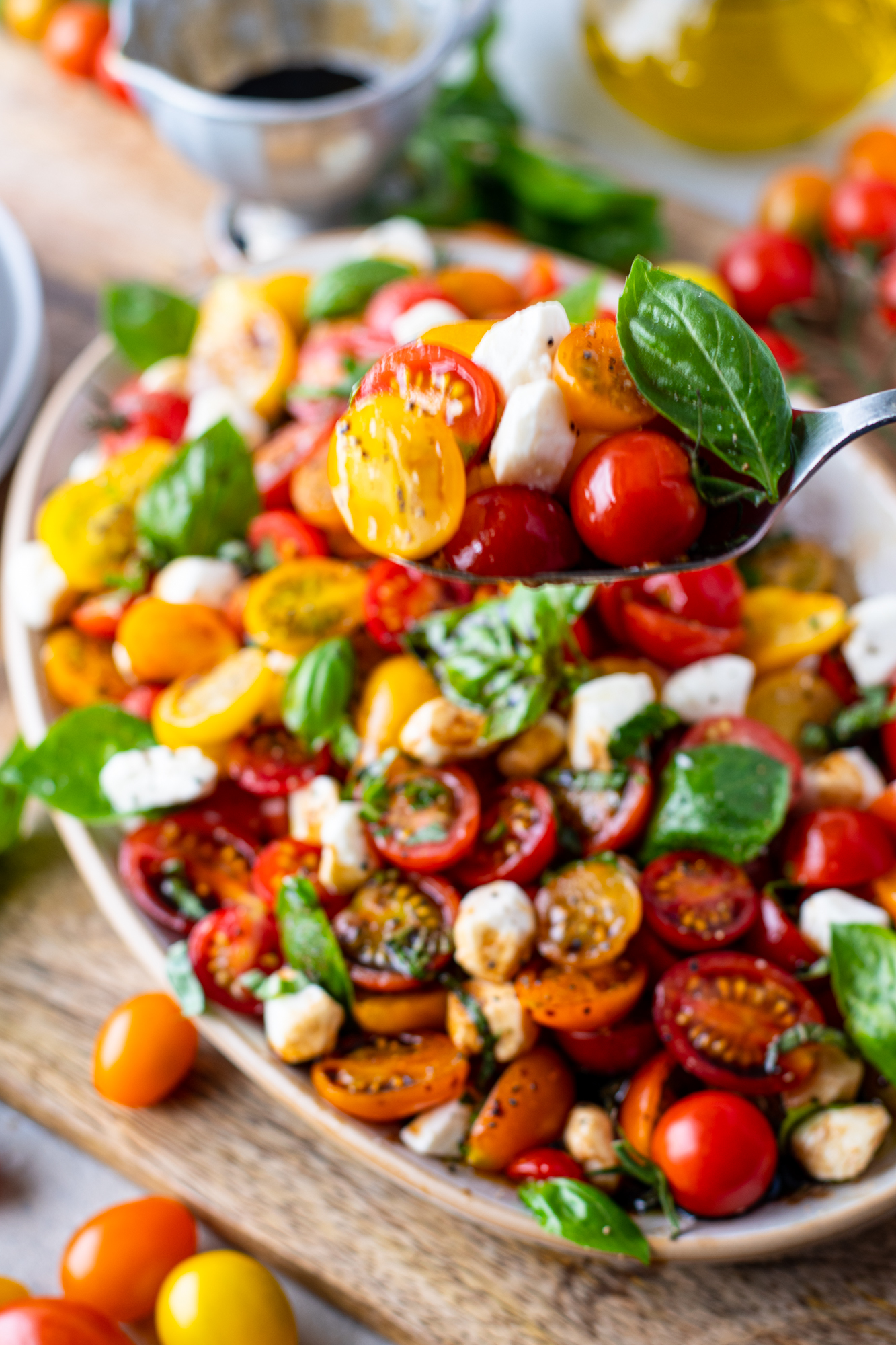 Caprese salad being removed from the serving tray with a silver spoon. 