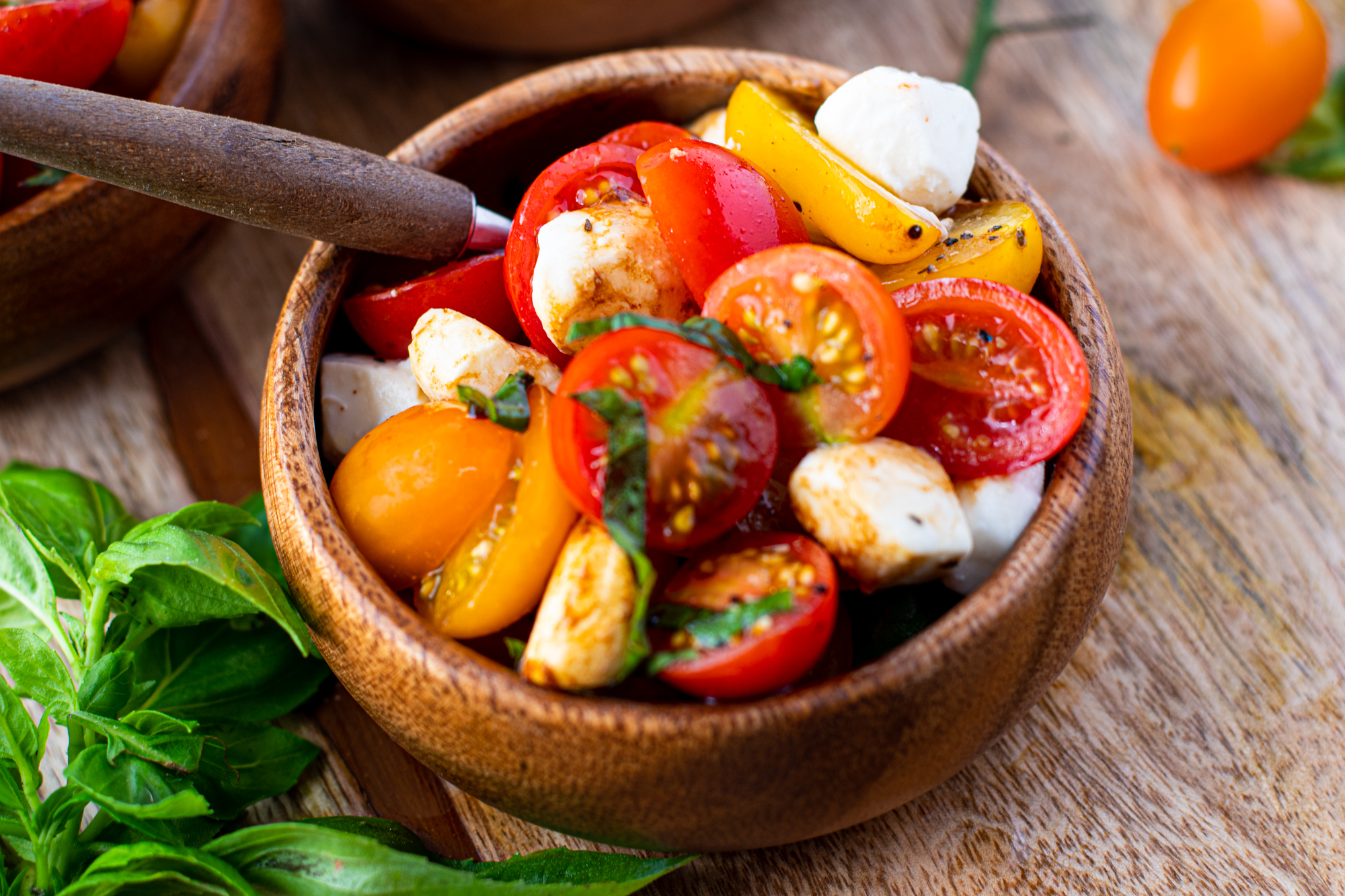 Salad in a wooden bowl topped with fresh basil. 