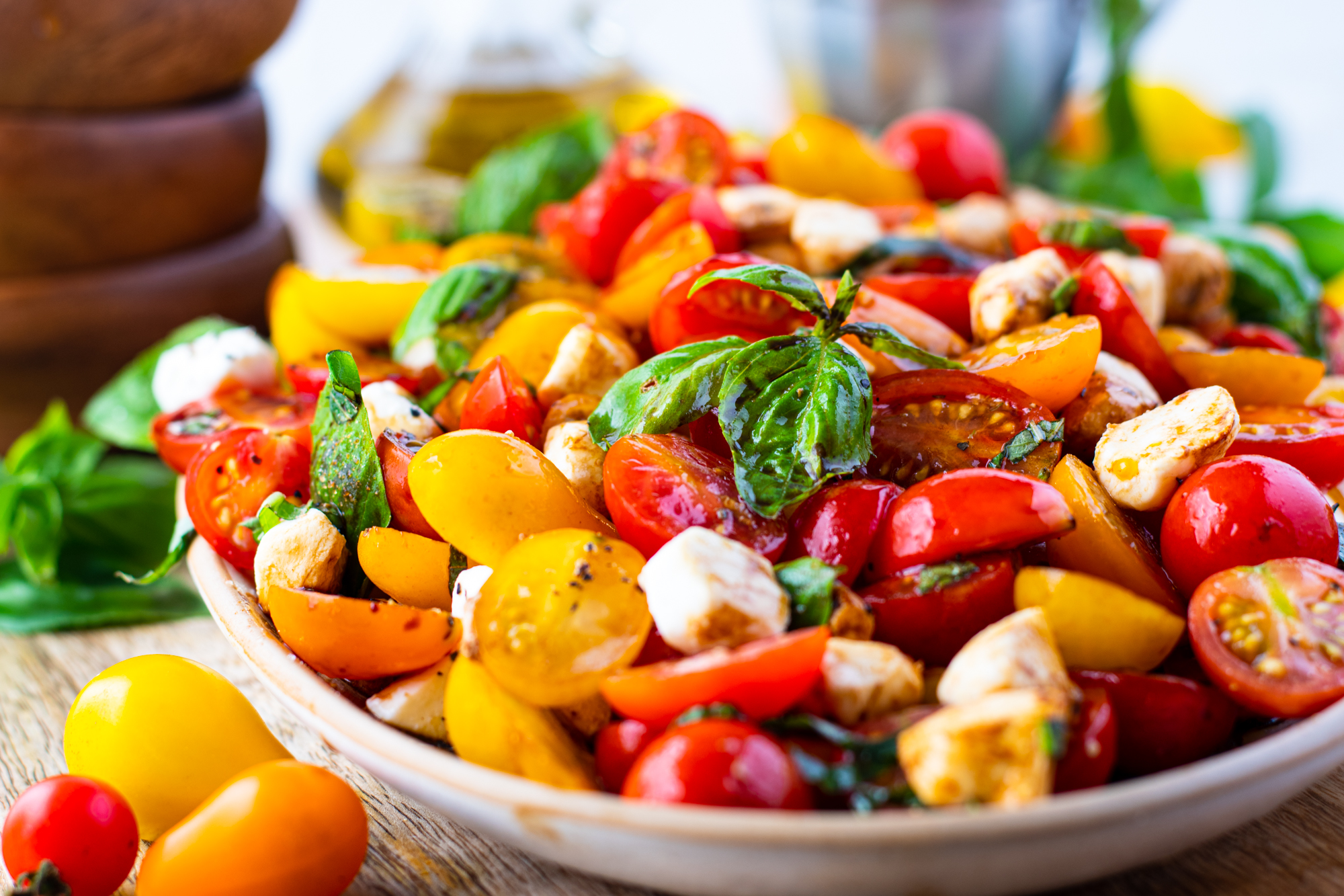 Side view of caprese salad in a white oval serving tray topped with fresh basil. 