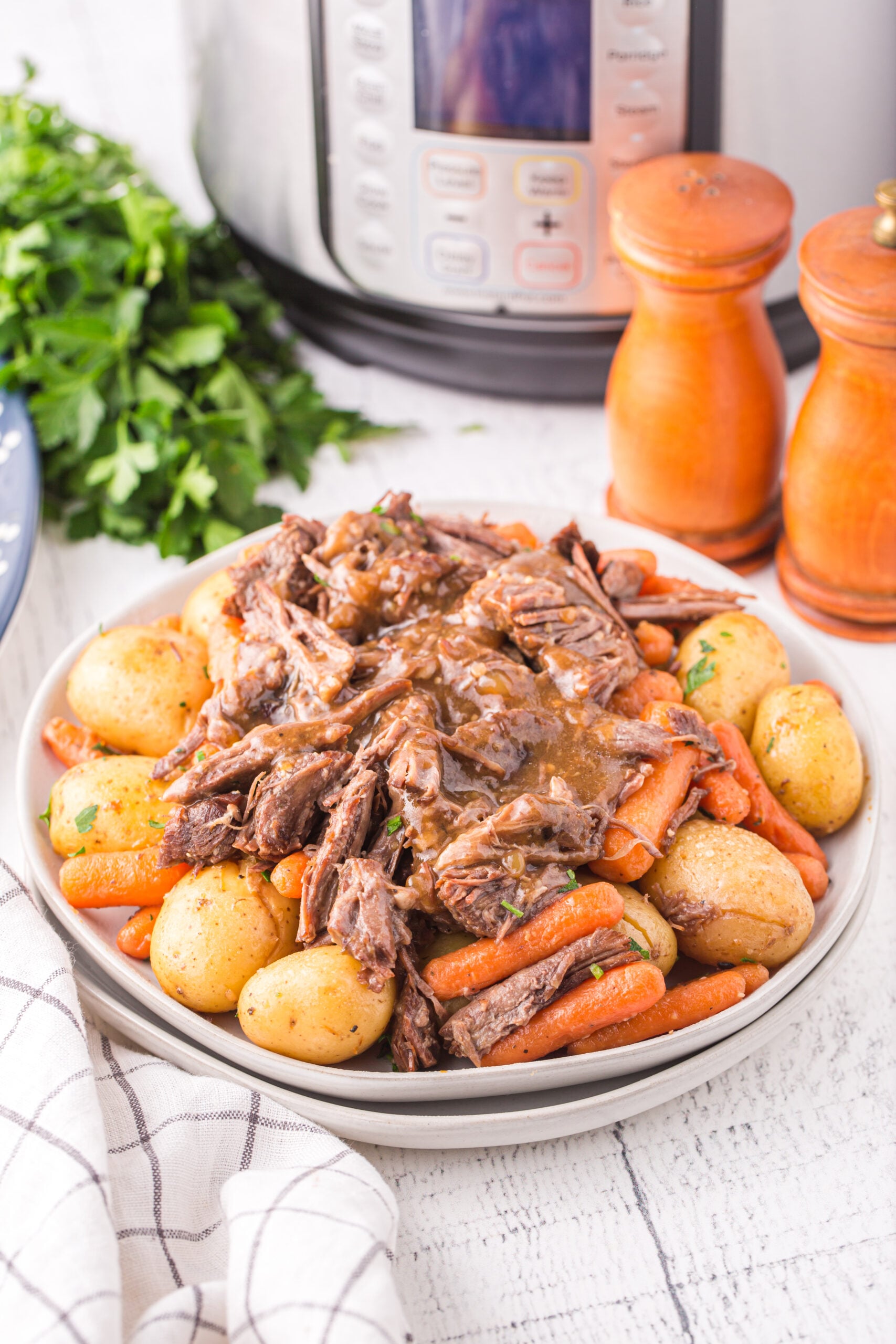 Instant Pot Pot Roast with potatoes and carrots on a white plate.