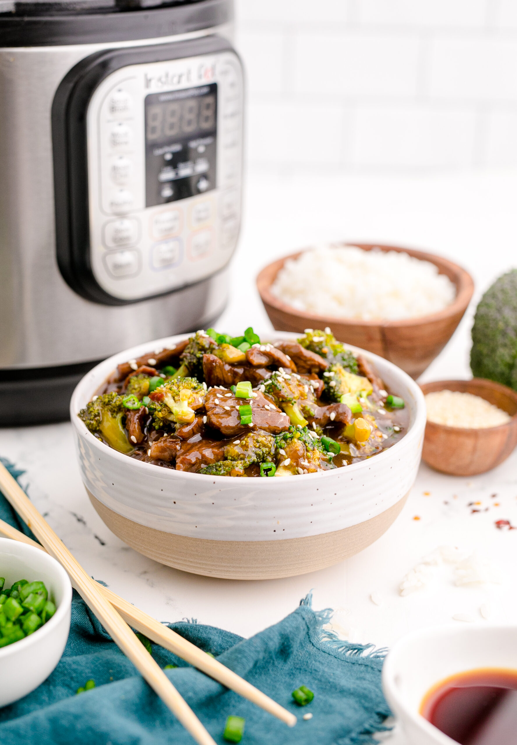 Side view of Instant Pot Beef and Broccoli in a white and tan bowl.