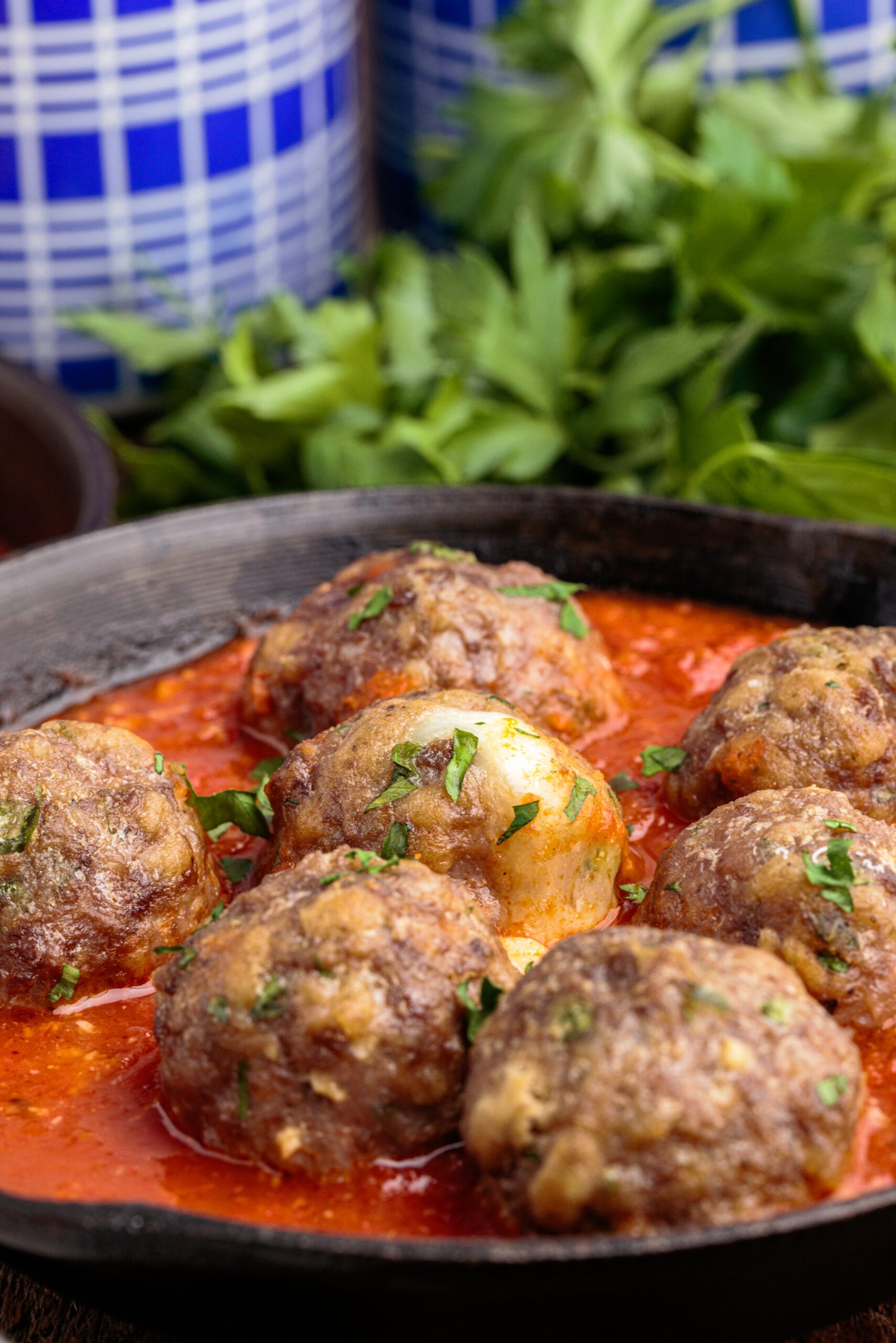 Side view of Mozzarella Stuffed Meatballs in a cast iron skillet.