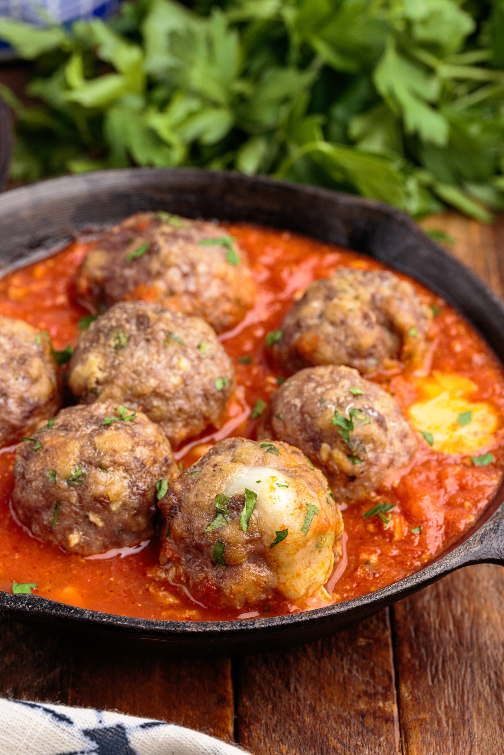 Side view of Mozzarella Stuffed Meatballs in a cast iron skillet.