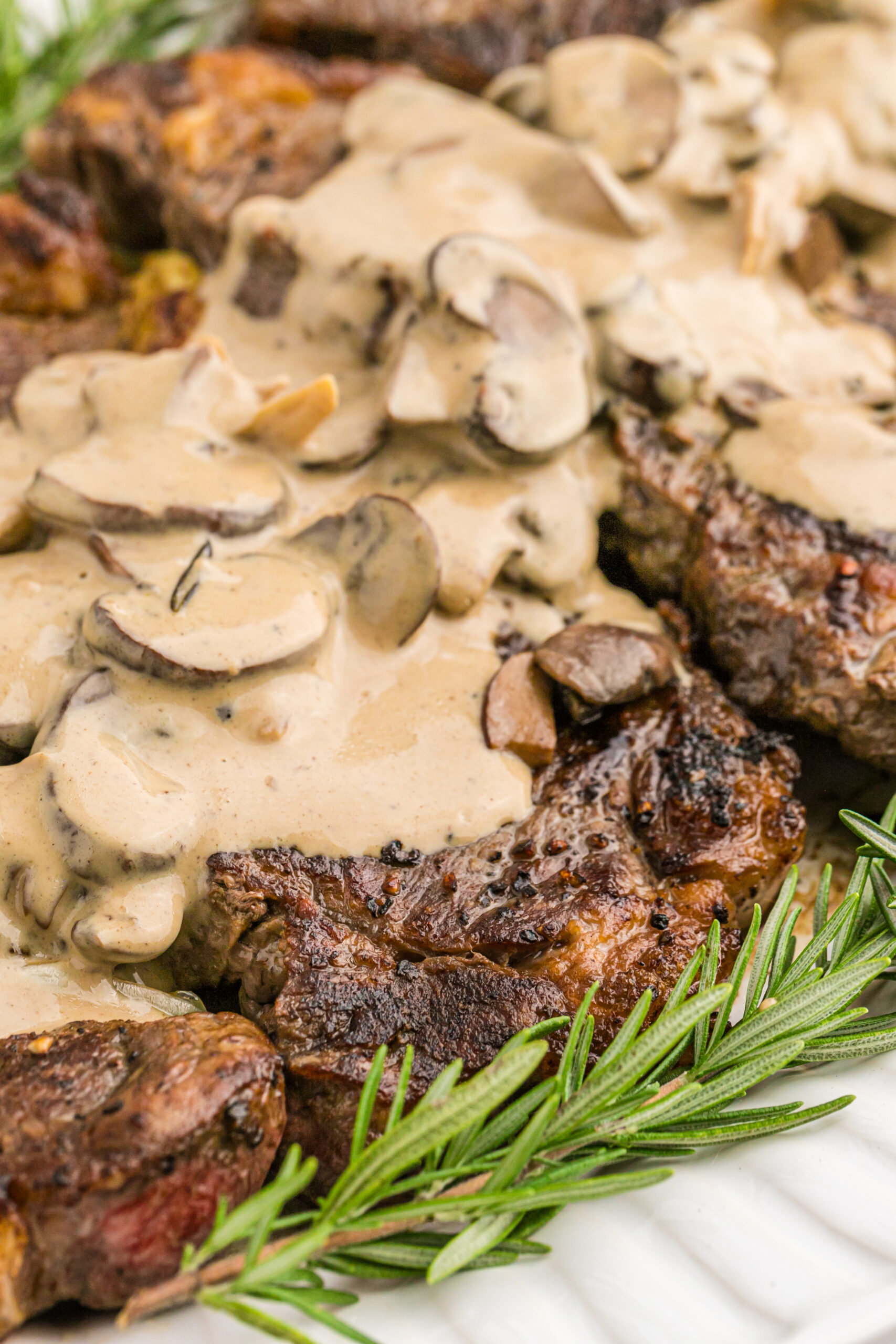 Close up view of Garlic Butter Steaks on a white serving dish.