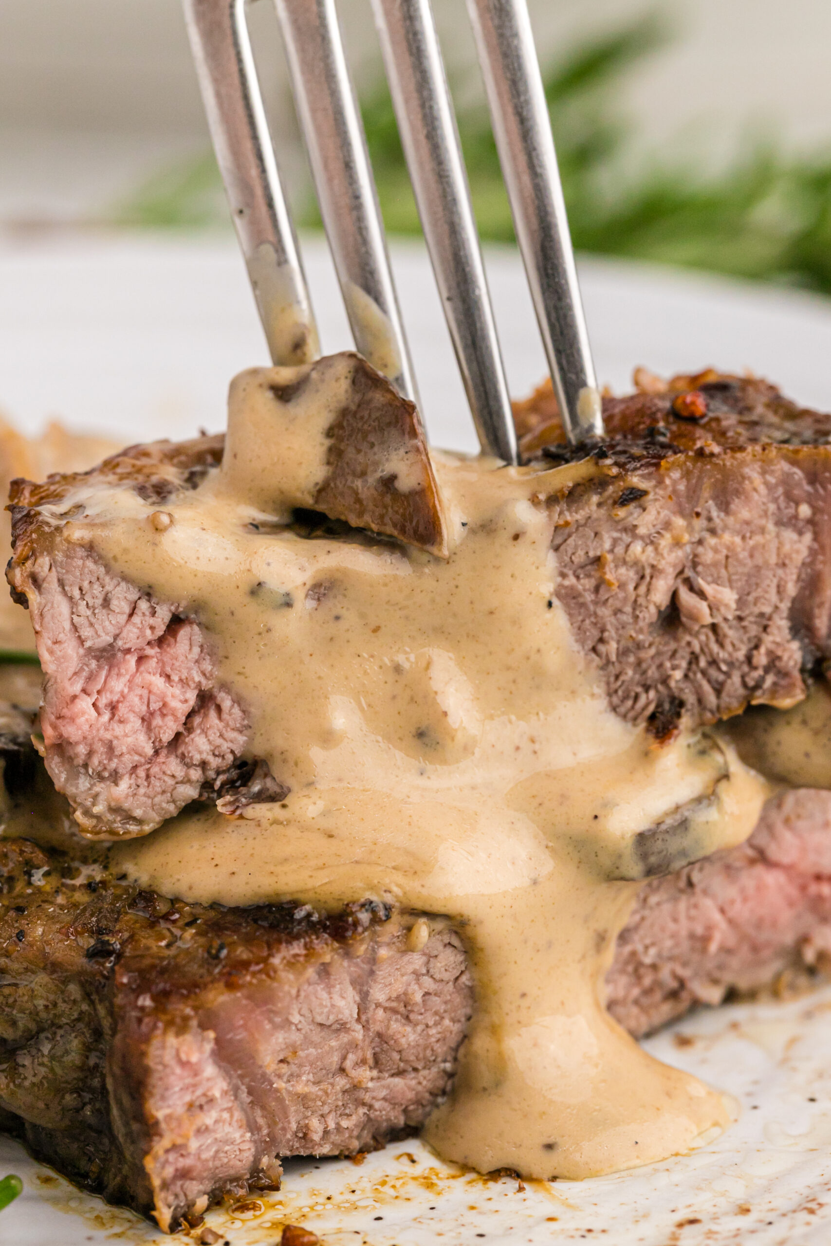 Close up view of Garlic Butter Steak cut in half and stacked with a silver fork.