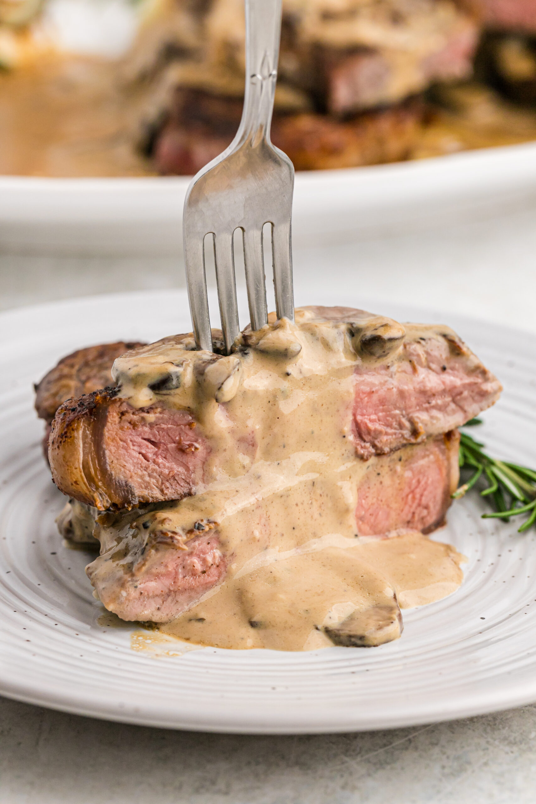 Front view of Garlic Butter Steak cut in half and stacked with a silver fork in the top half.