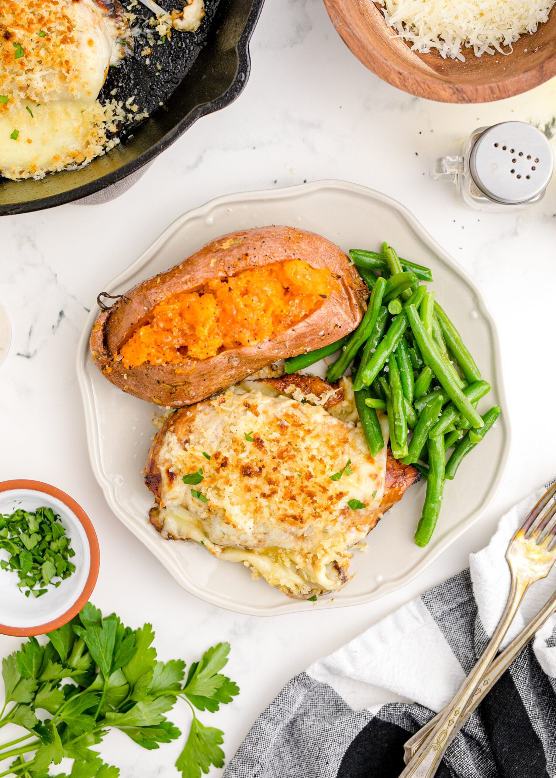 Overhead view of Parmesan Crusted Chicken (Longhorn Copycat) on a white dish served with green beans and baked sweet potato.