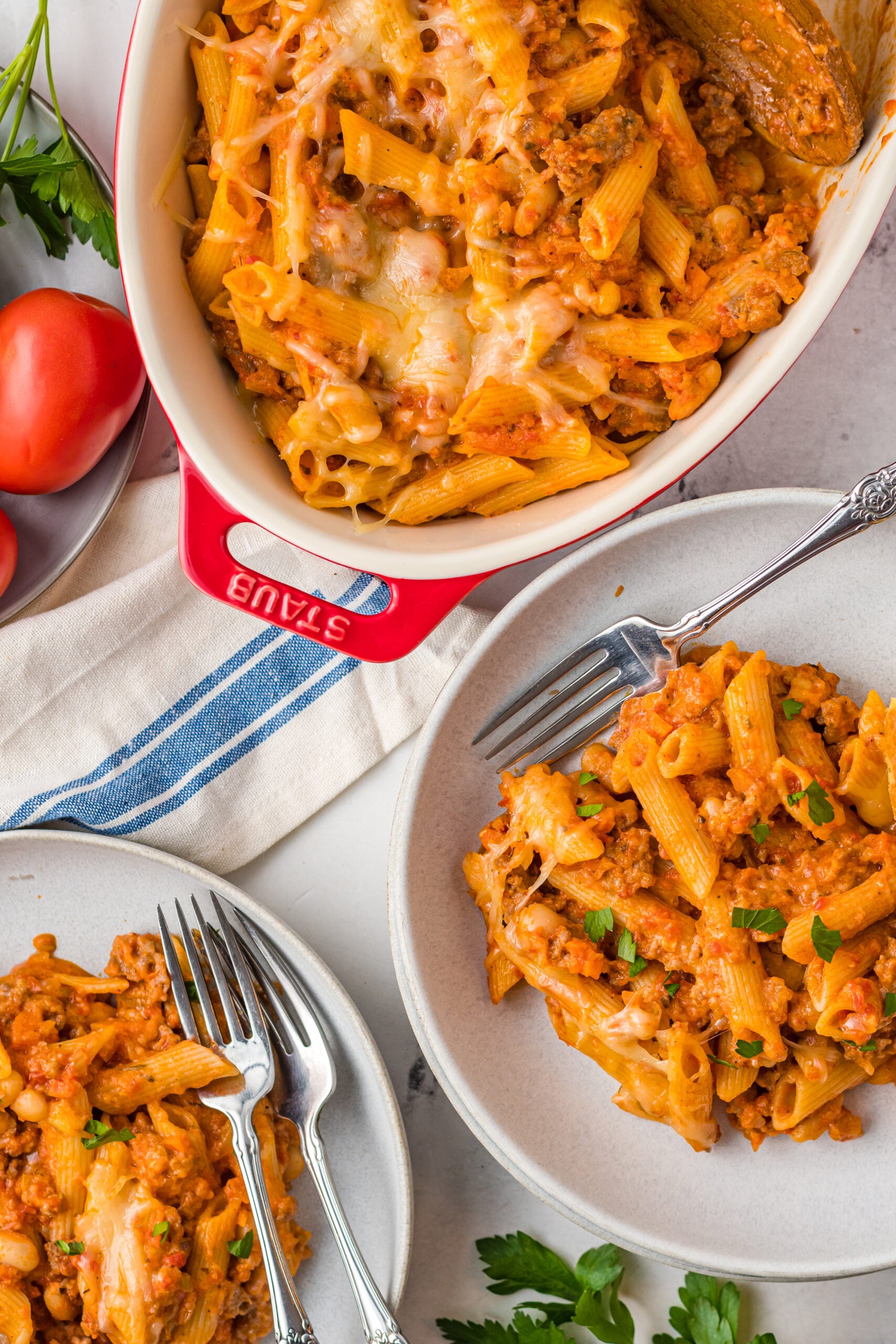 Overhead view of two servings of Pasta Fagioli al Forno on two gray dishes with silver forks.