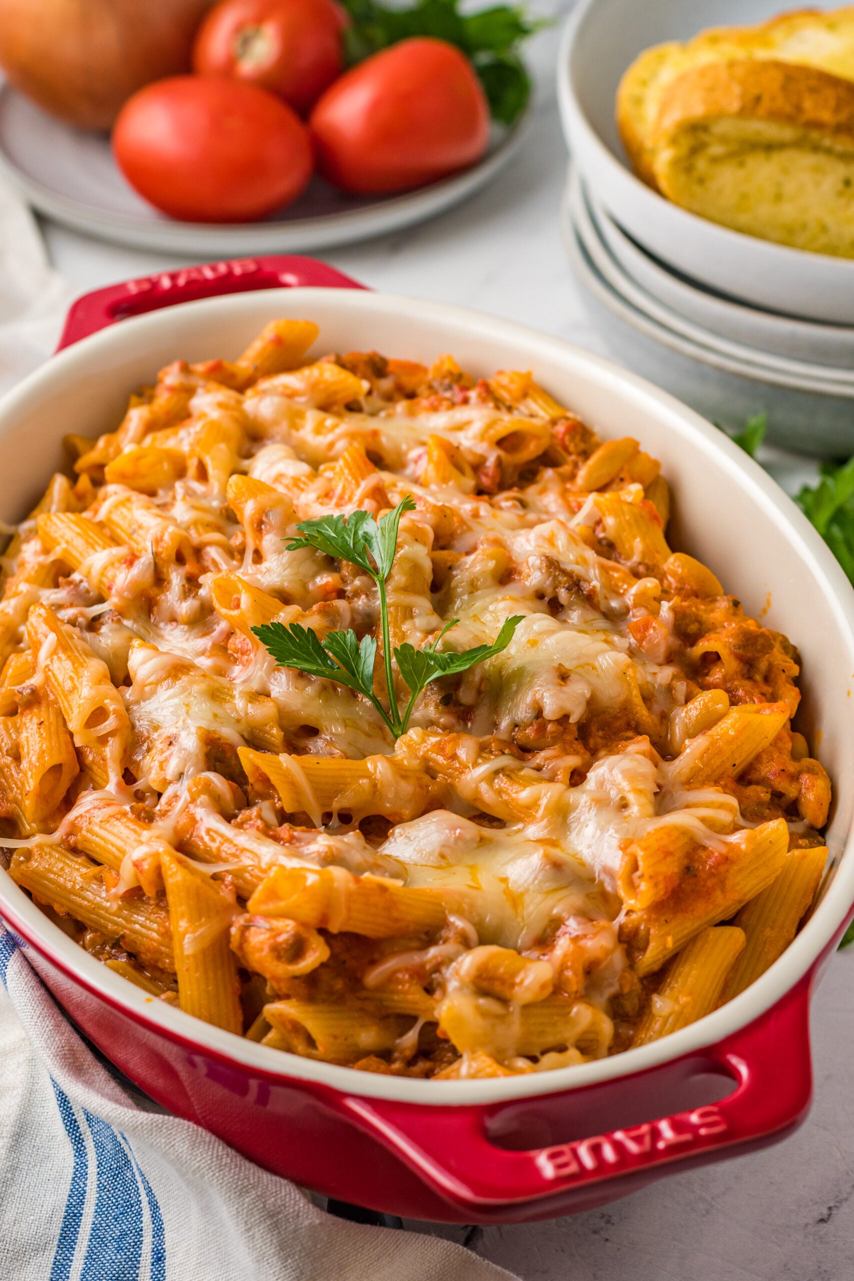 Close up view of Pasta Fagioli al Forno in a baking dish with a wooden spoon scooping a serving.