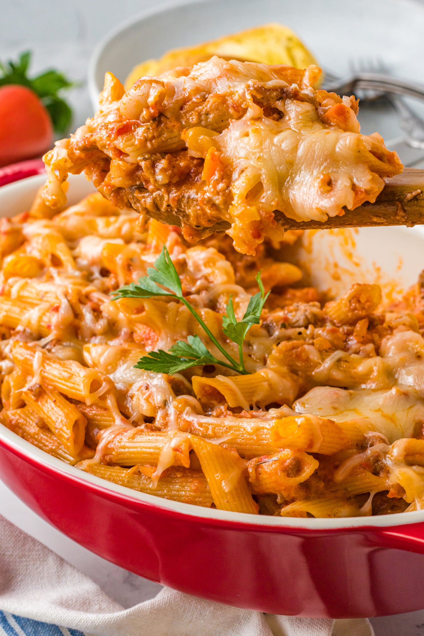 Pasta Fagioli al Forno in a baking dish with a wooden spoon scooping a serving.