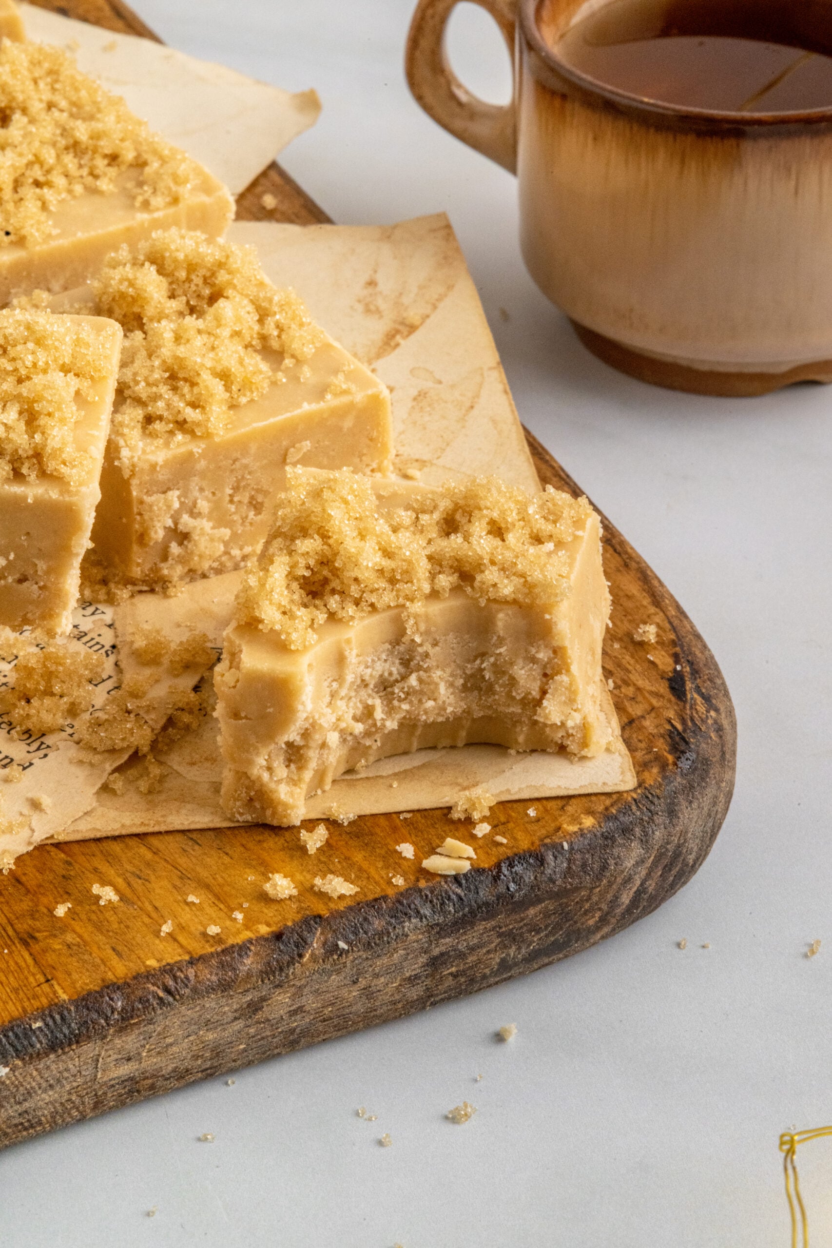 Penuche Fudge with a bite taken out on a wooden board.