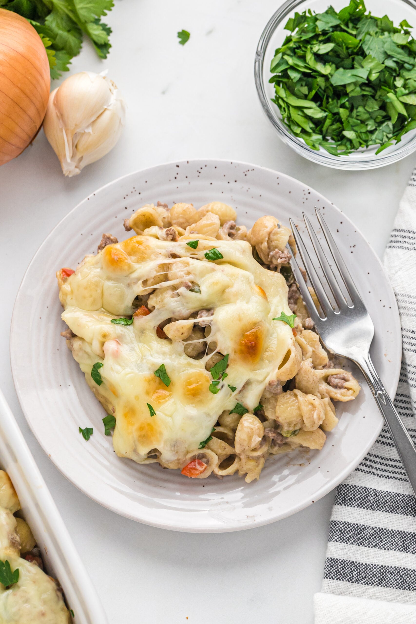 Overhead view of Philly Cheesesteak Casserole on a white dish served with a silver fork.