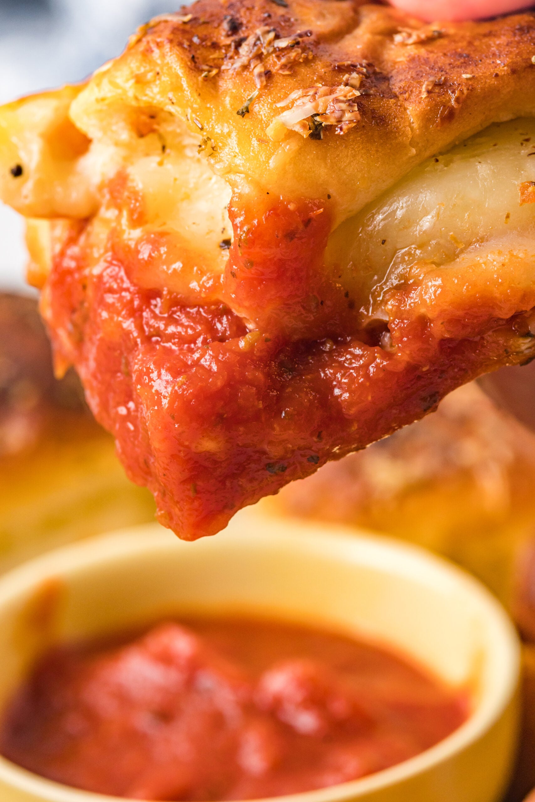 Close up view of a pizza slider after being dipped in marinara sauce.