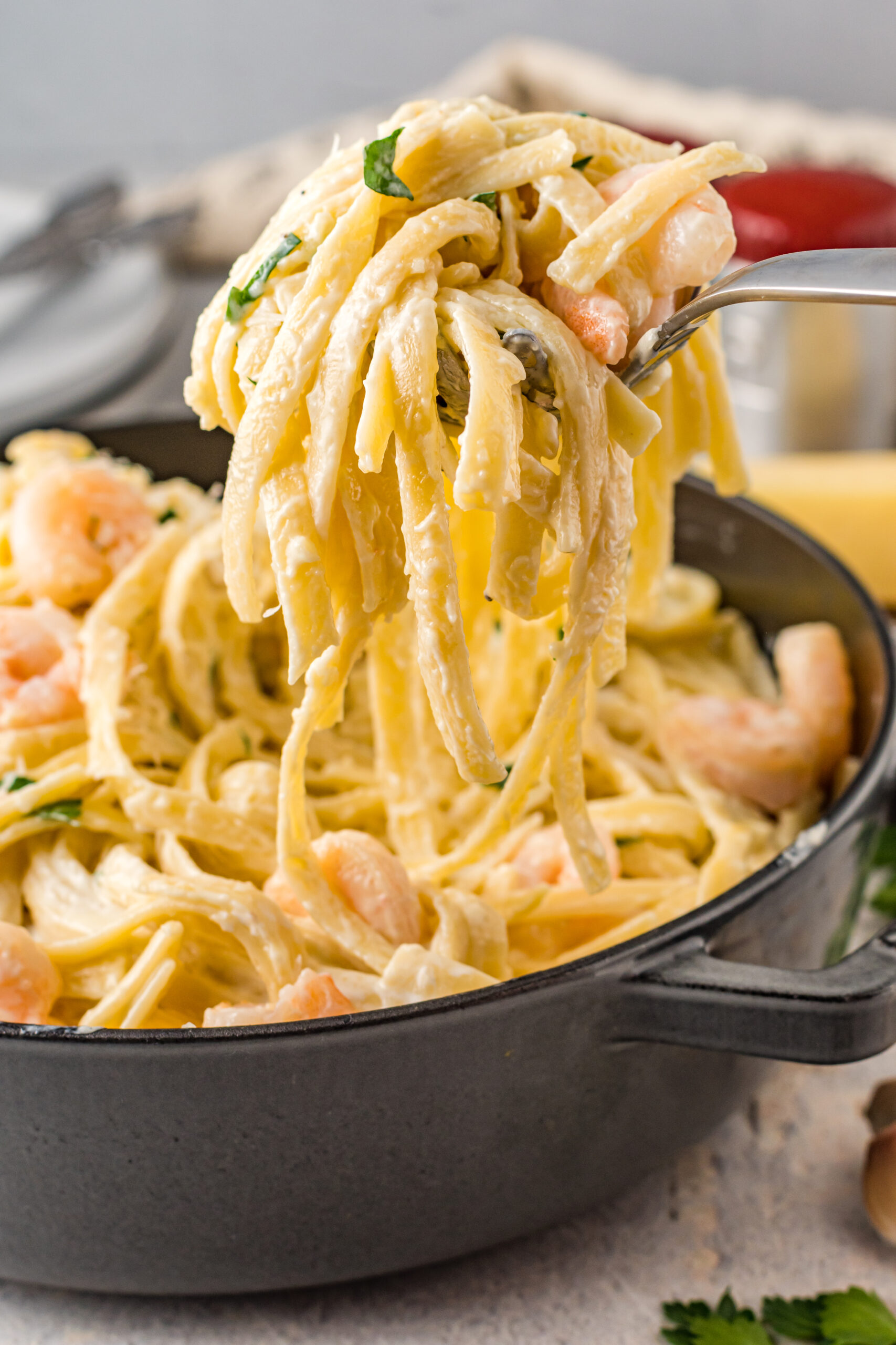 Front view of a silver serving spoon scooping out Shrimp Alfredo.