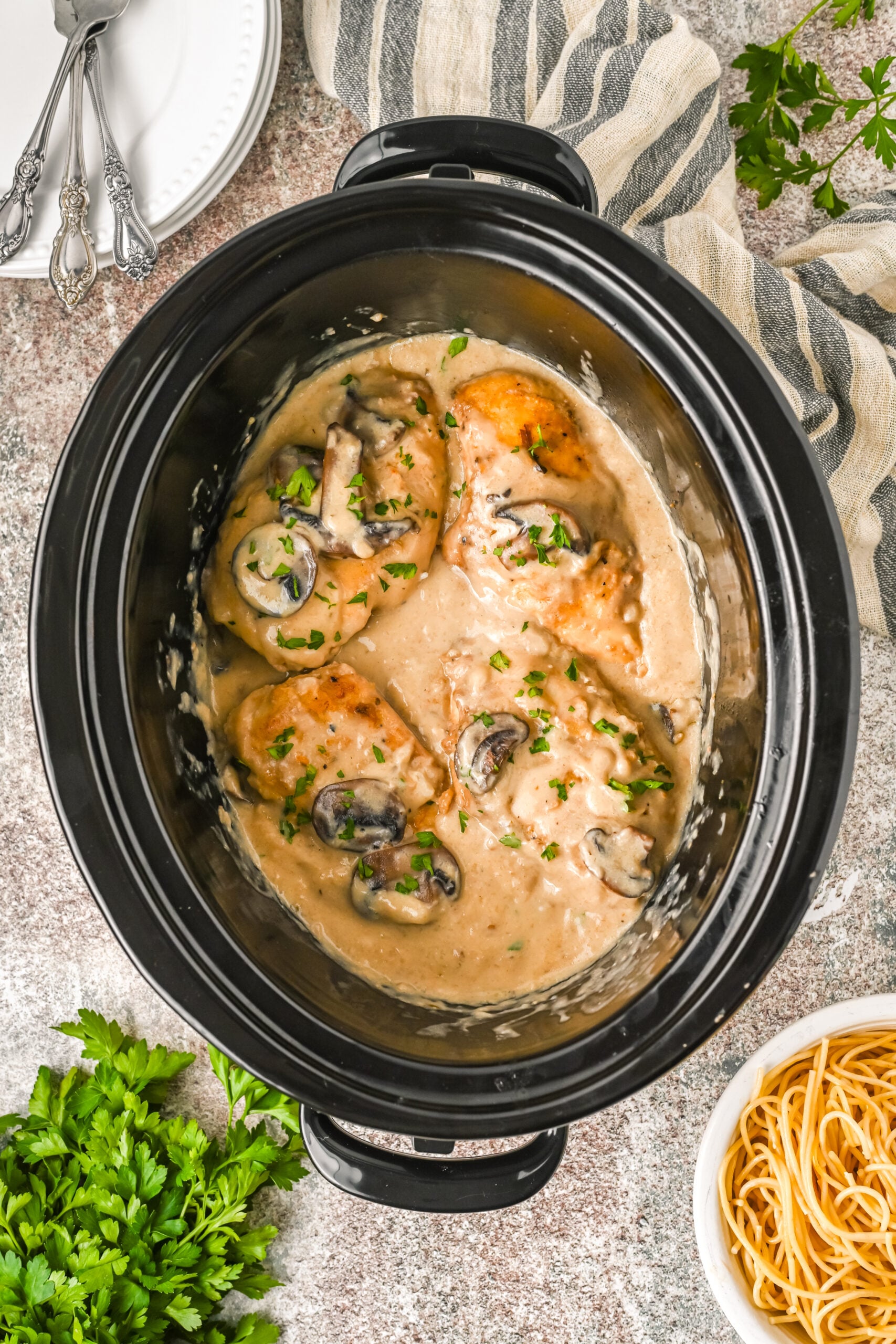 Overhead shot of slow cooker chicken marsala in the slow cooker inner pot topped with fresh parsley.