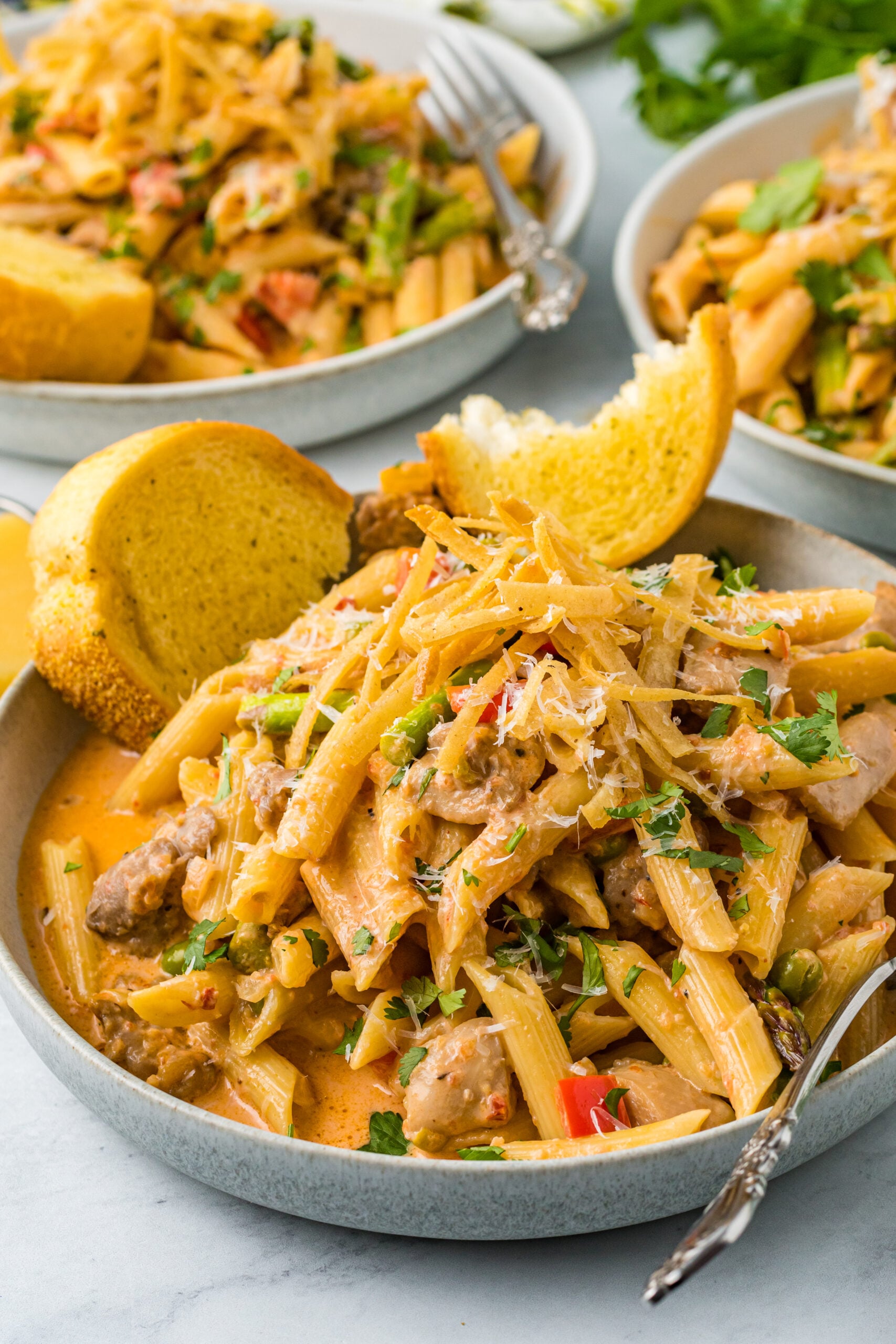 Side view of Cajun Chicken Pasta served in a dish with garlic bread.