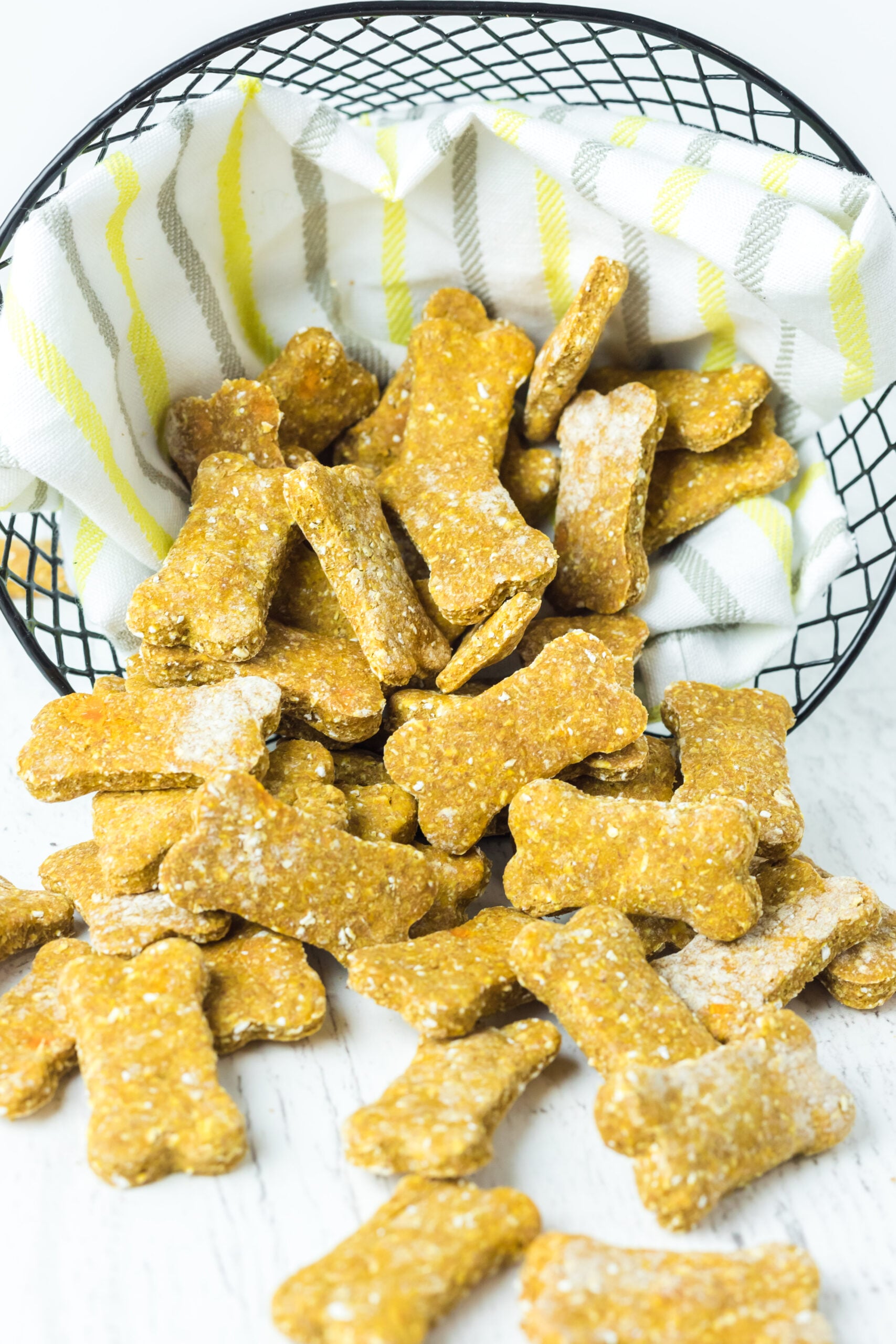 Front view of Sweet Potato and Pumpkin Dog Treats spilling out of a wire basket lined with linen.