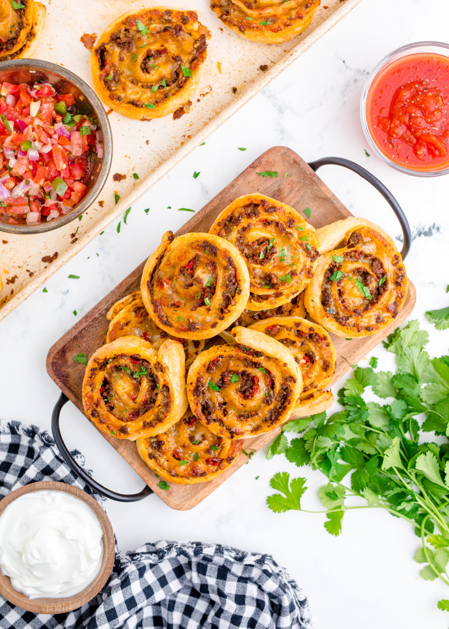Overhead view of Taco Pinwheels stacked on a wooden cutting board.
