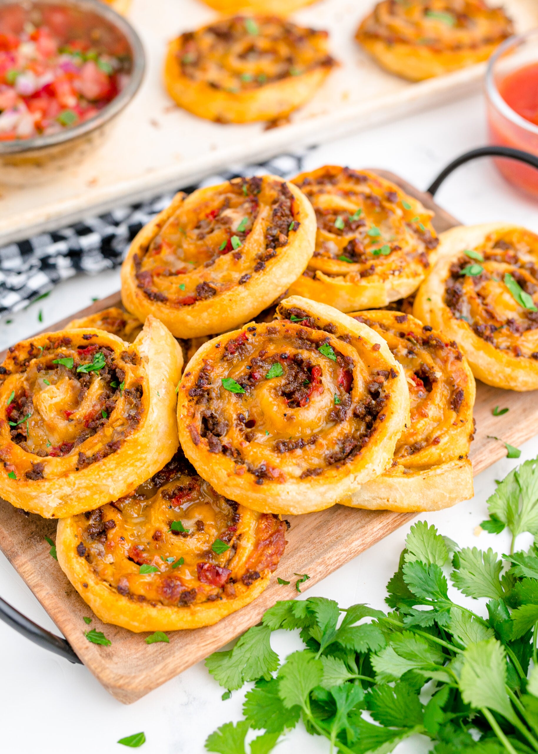  Side view of Taco Pinwheels stacked on a wooden cutting board.