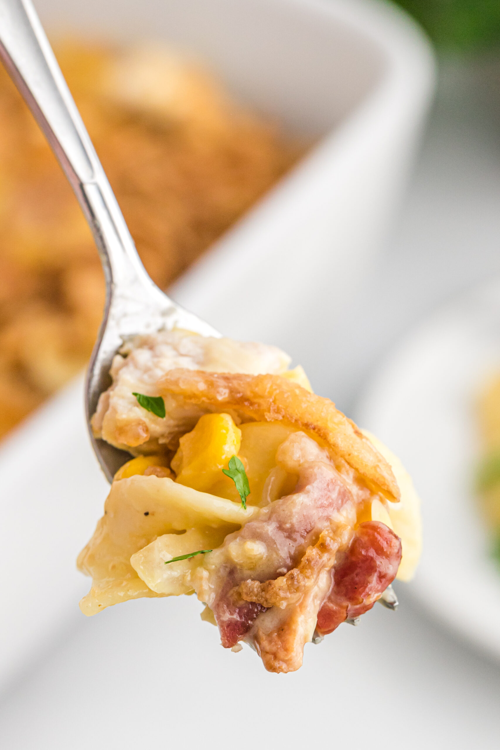 Close up view of a silver spoon with a spoon full of Ultimate Chicken Casserole.