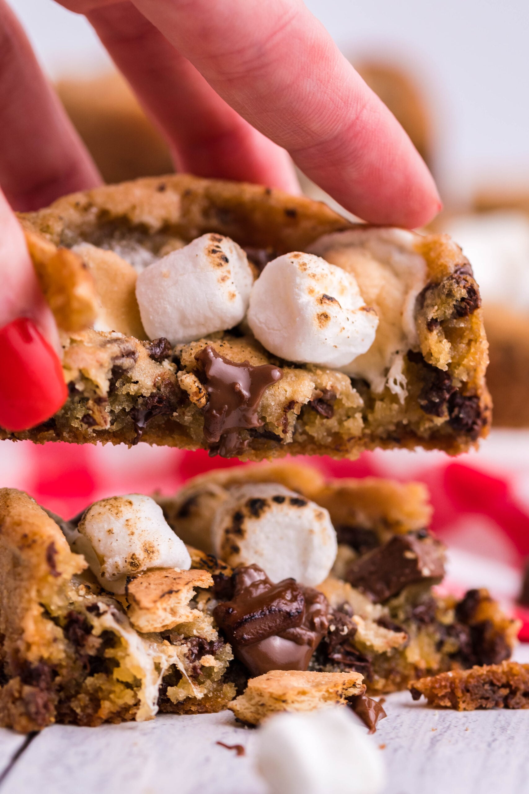 Front view of two halves of Deep Dish S’mores Cookies with one half being held.