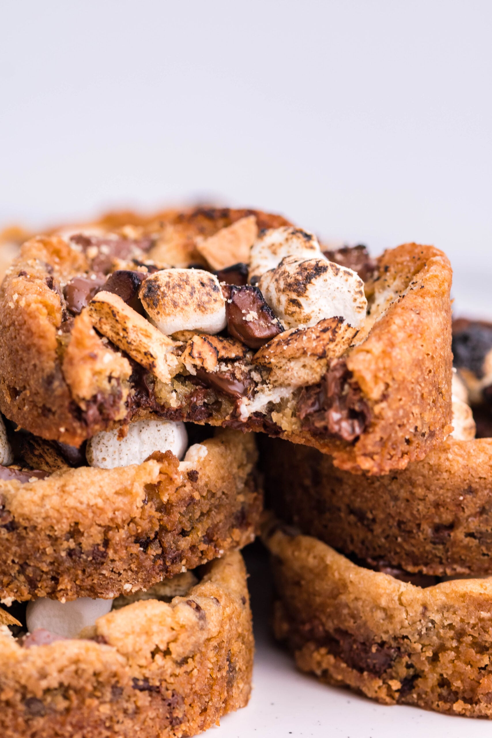 Front view of five Deep Dish S’mores Cookies staked with a bite removed from the top cookie.