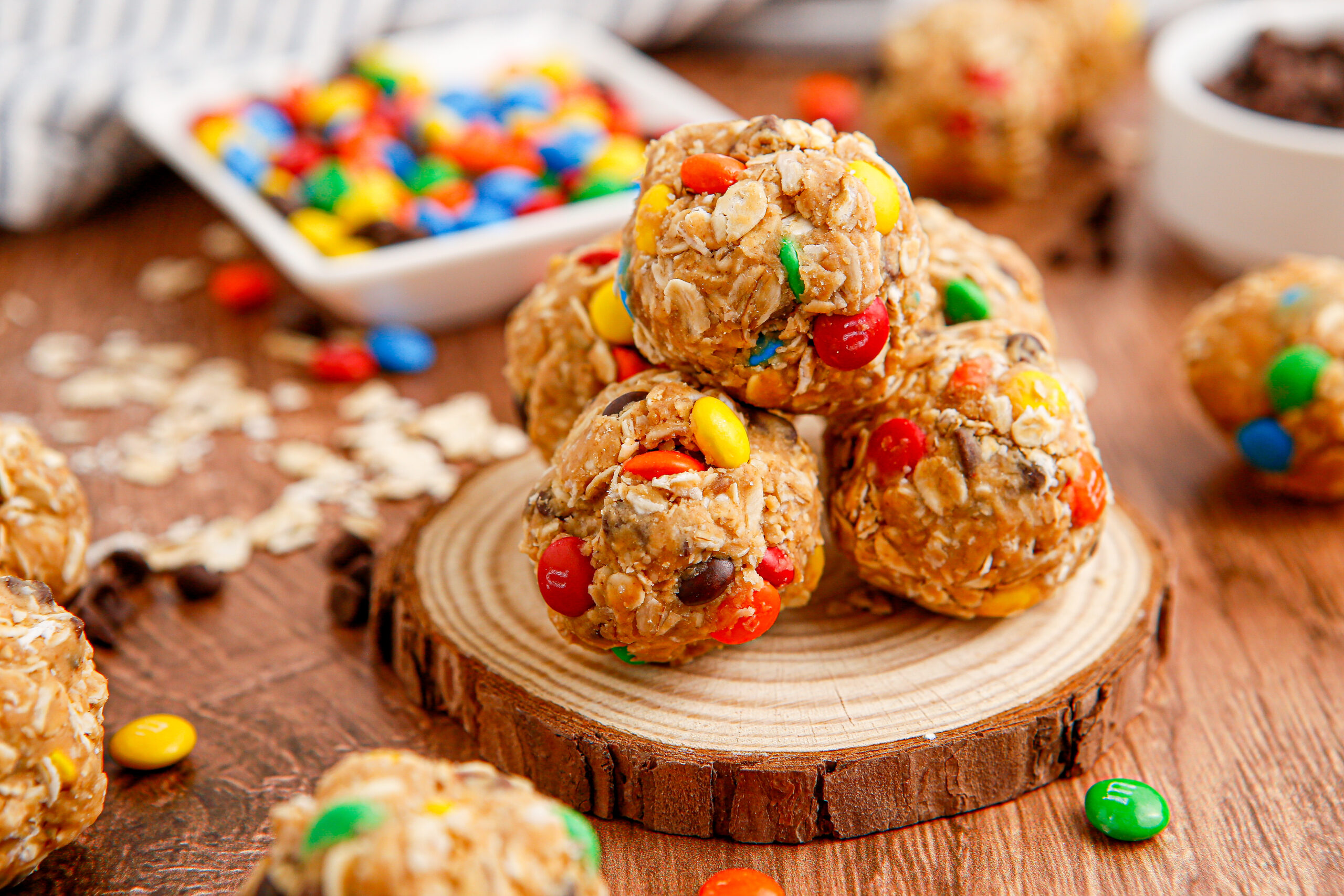 Close up view of No Bake M&M Energy balls on a small wooden serving platter