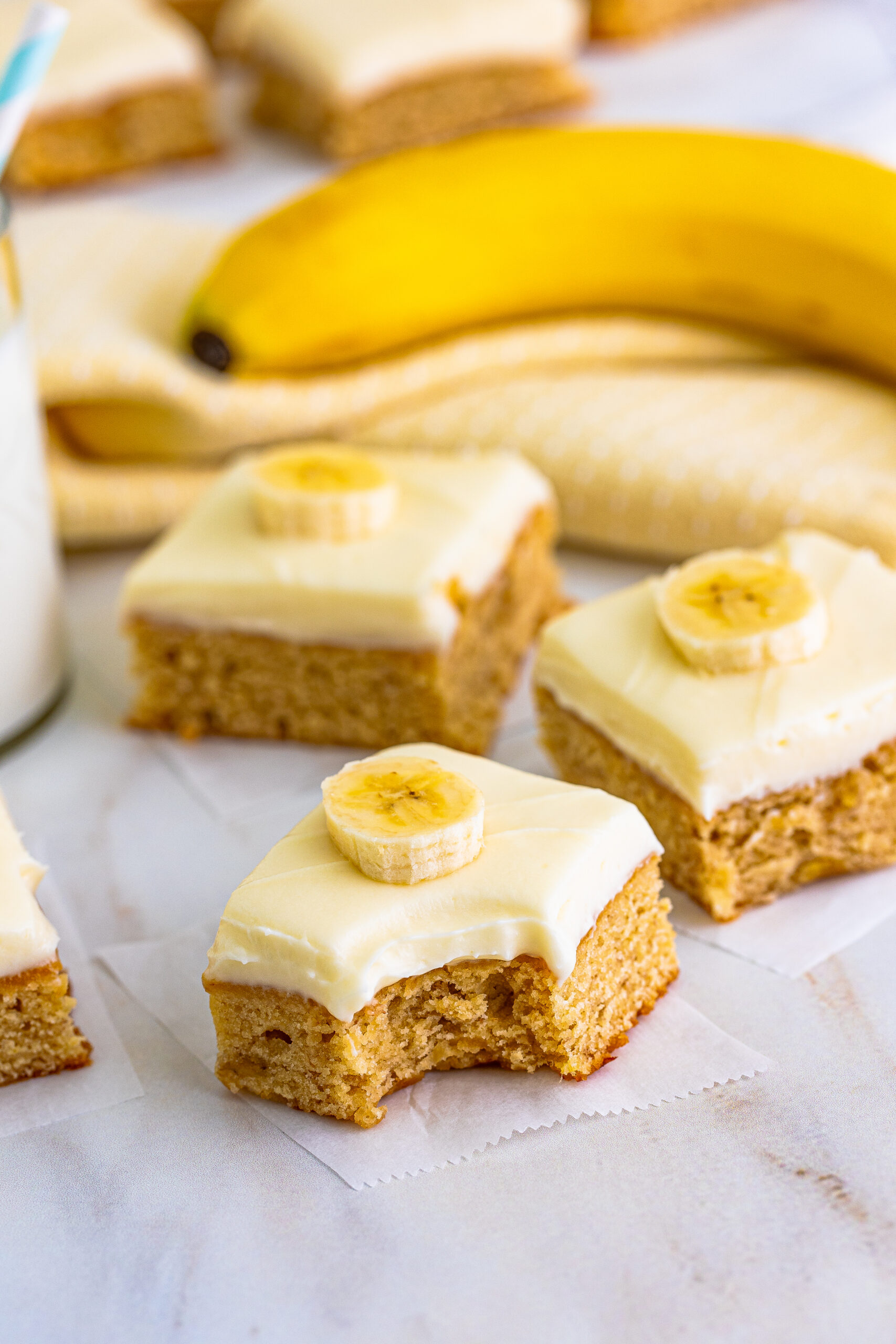 Front view of Banana Brownies on parchment paper with a bite removed from the front brownie.