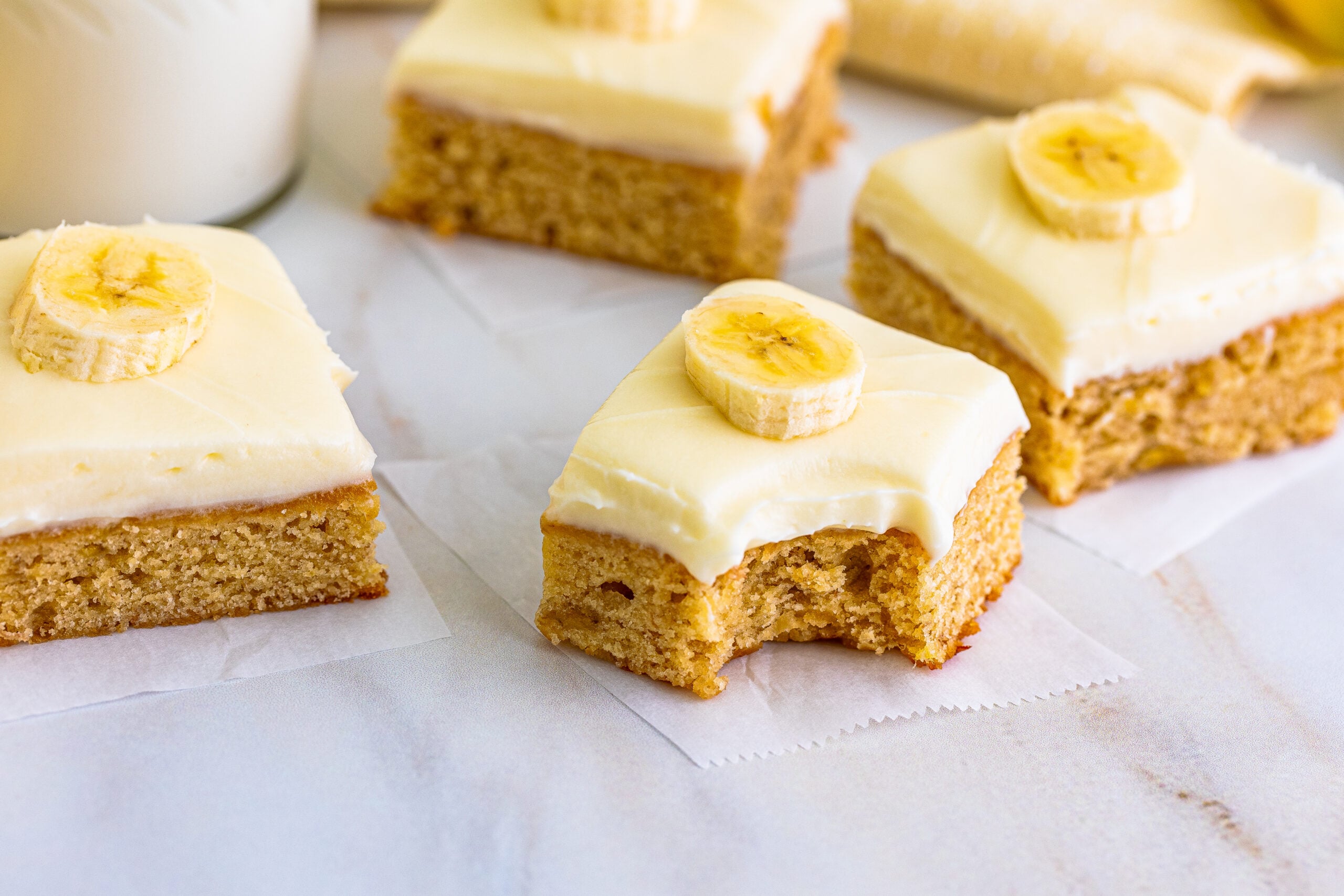 Front view of Banana Brownies on parchment paper with a bite removed from the front brownie.
