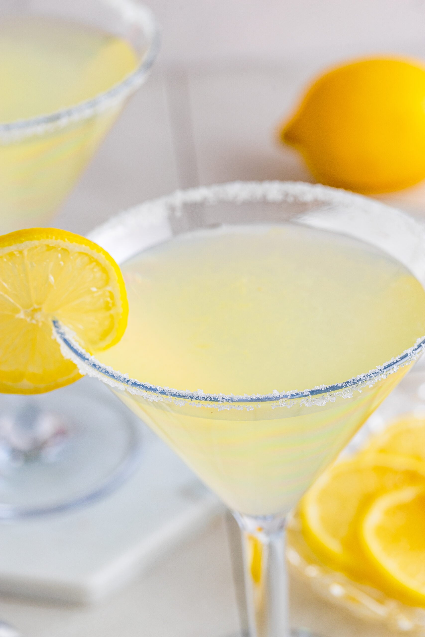 Close up shot of lemon drop martini in a martini glass with a lemon slice. 