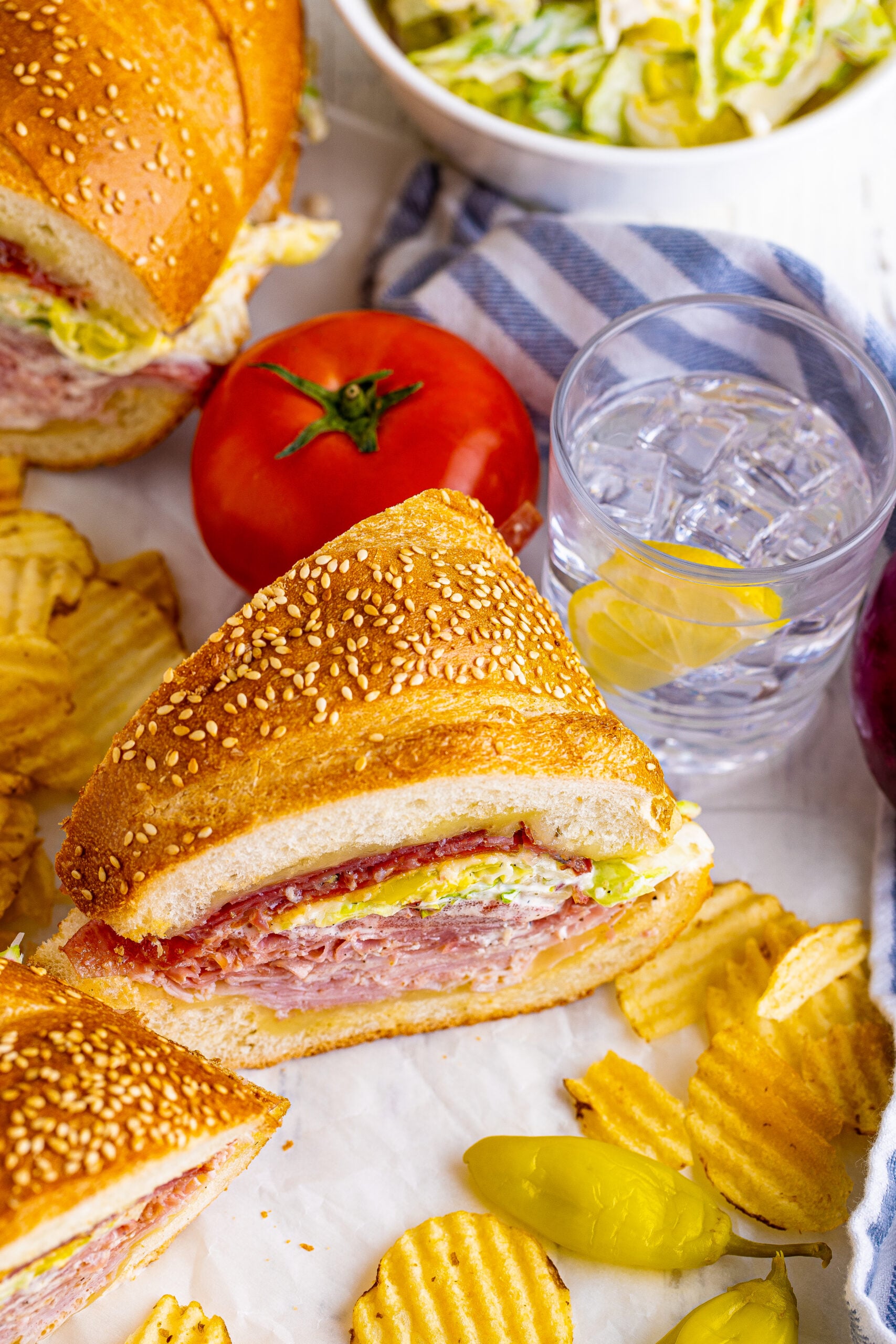 45 degree view of Grinder Subs on parchment paper surrounded by wavy chips.