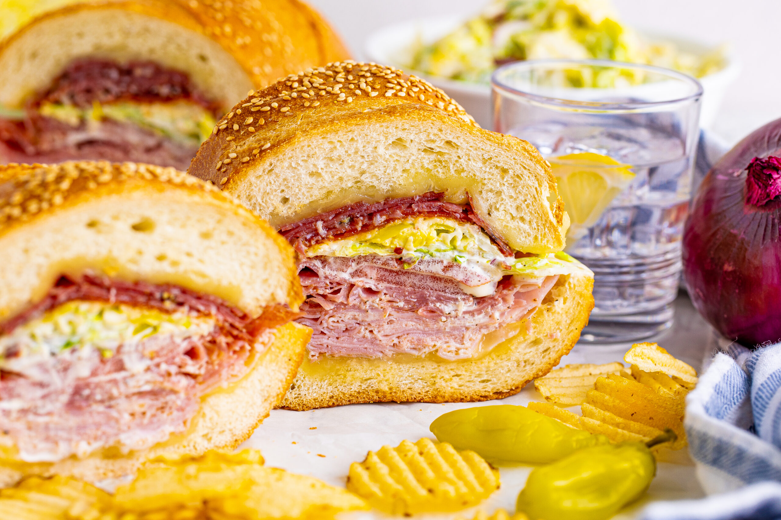 Front view of Grinder Subs on parchment paper surrounded by wavy chips.