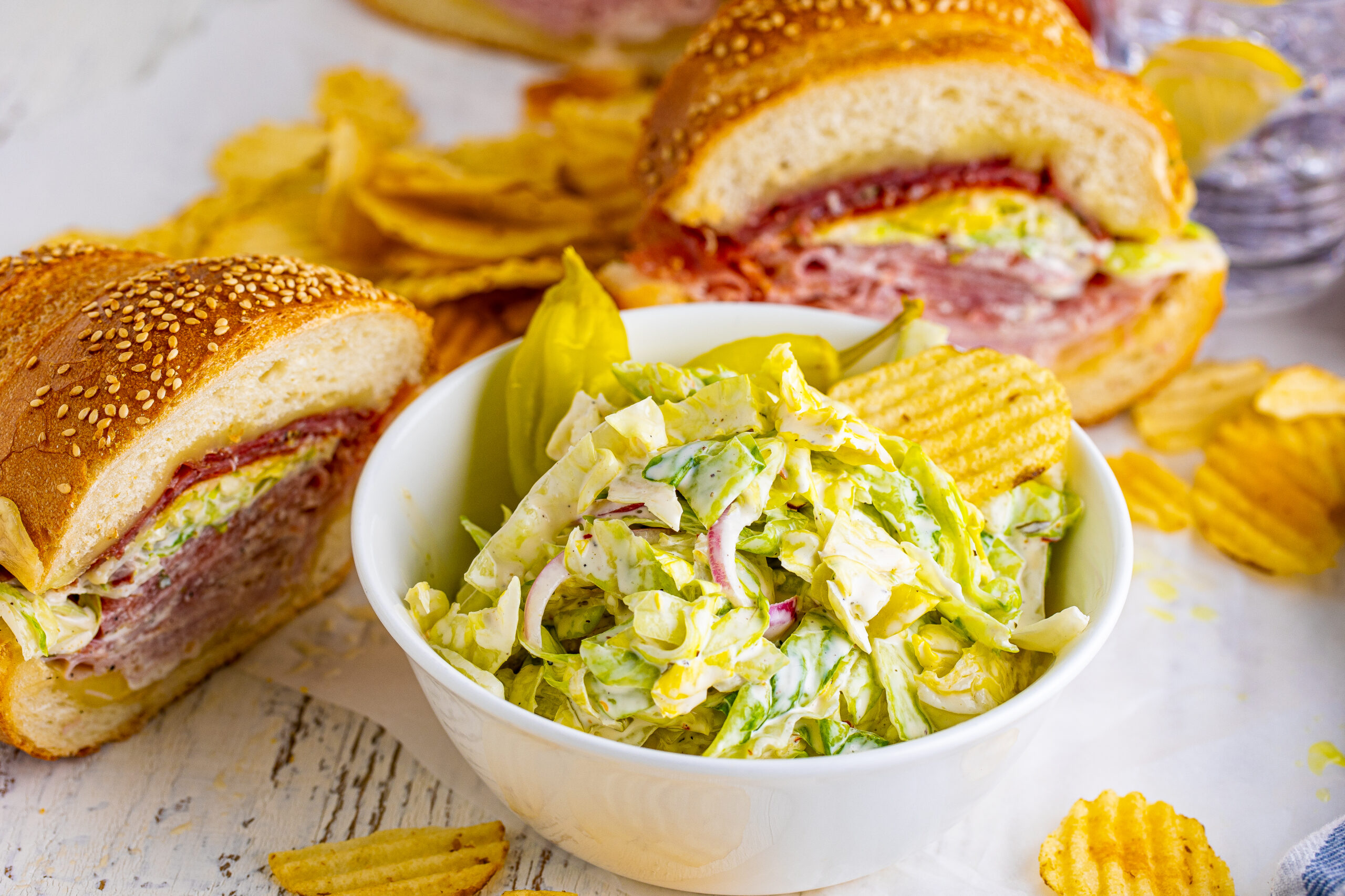 Grinder salad in a white bowl with the sliced grinder sub in the background
