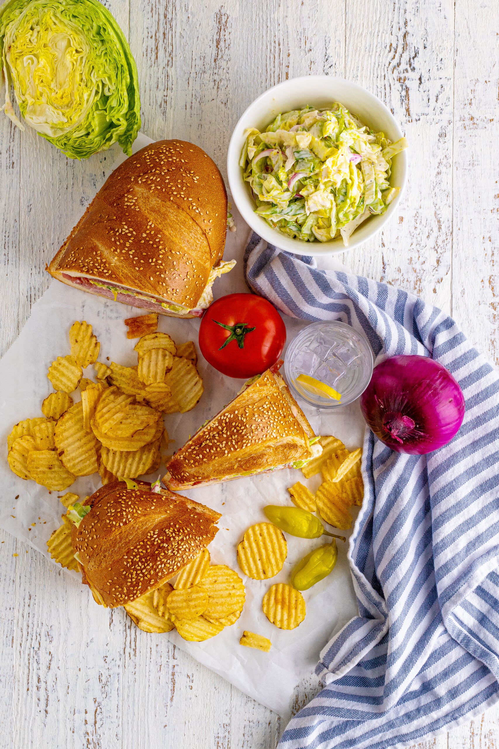 Overhead view of Grinder Subs on a piece of parchment paper surrounded with wavy chips.