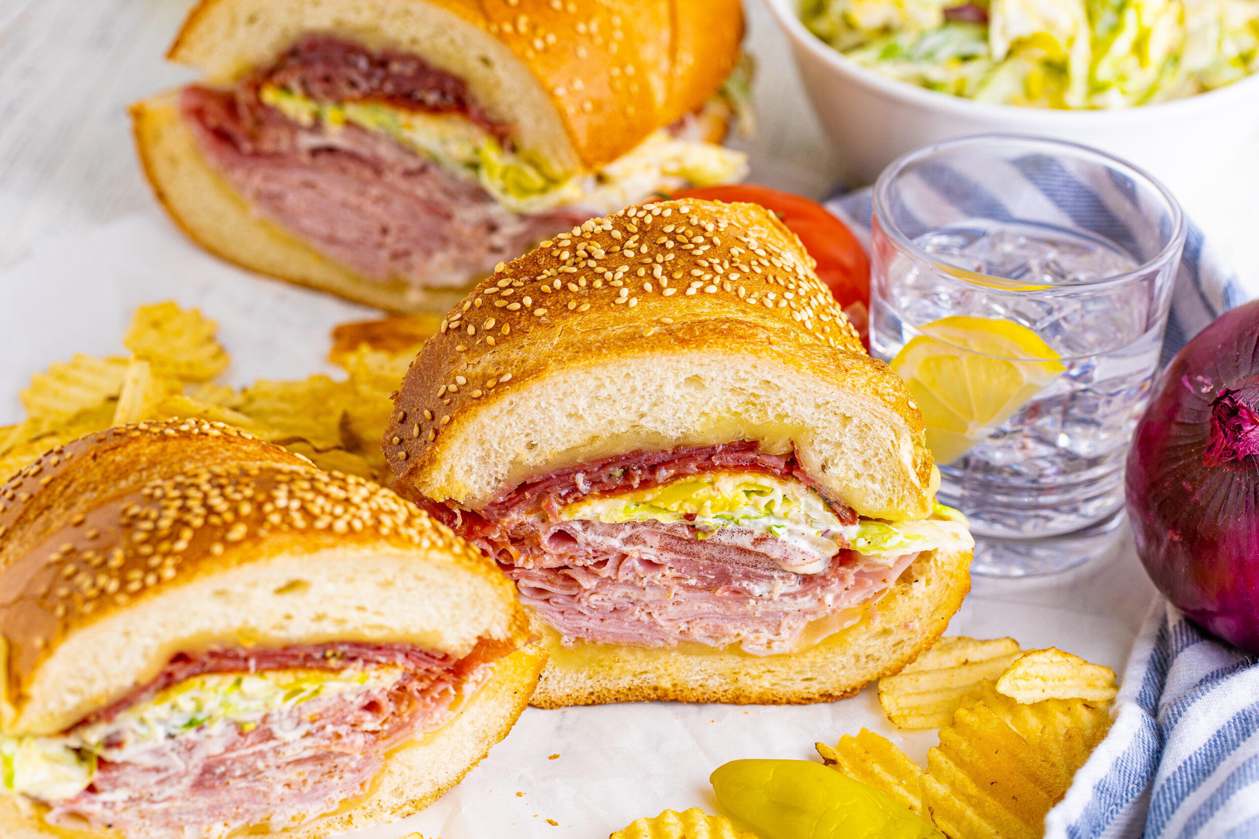 Front view of Grinder Subs on parchment paper surrounded by wavy chips.
