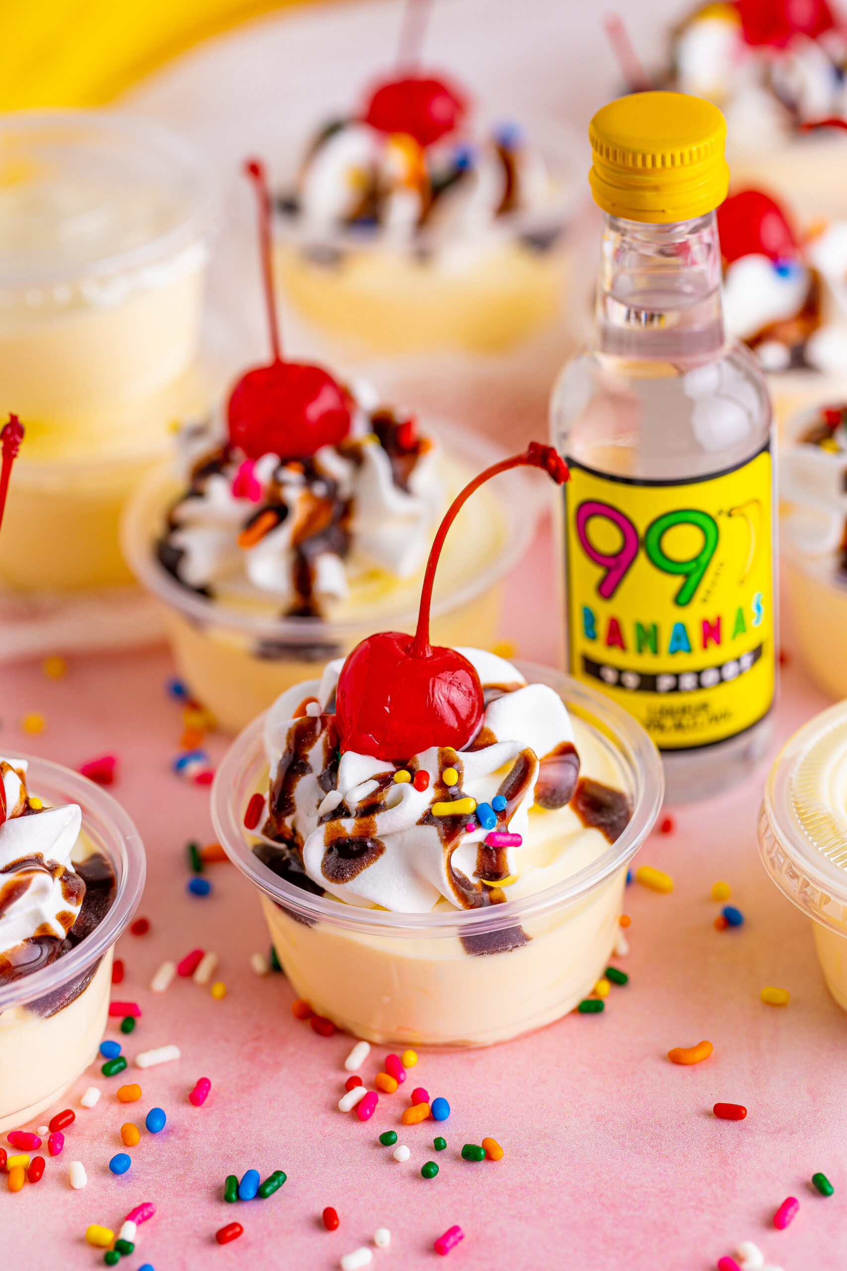 Side view of Banana Split Shots surrounded by rainbow sprinkles.