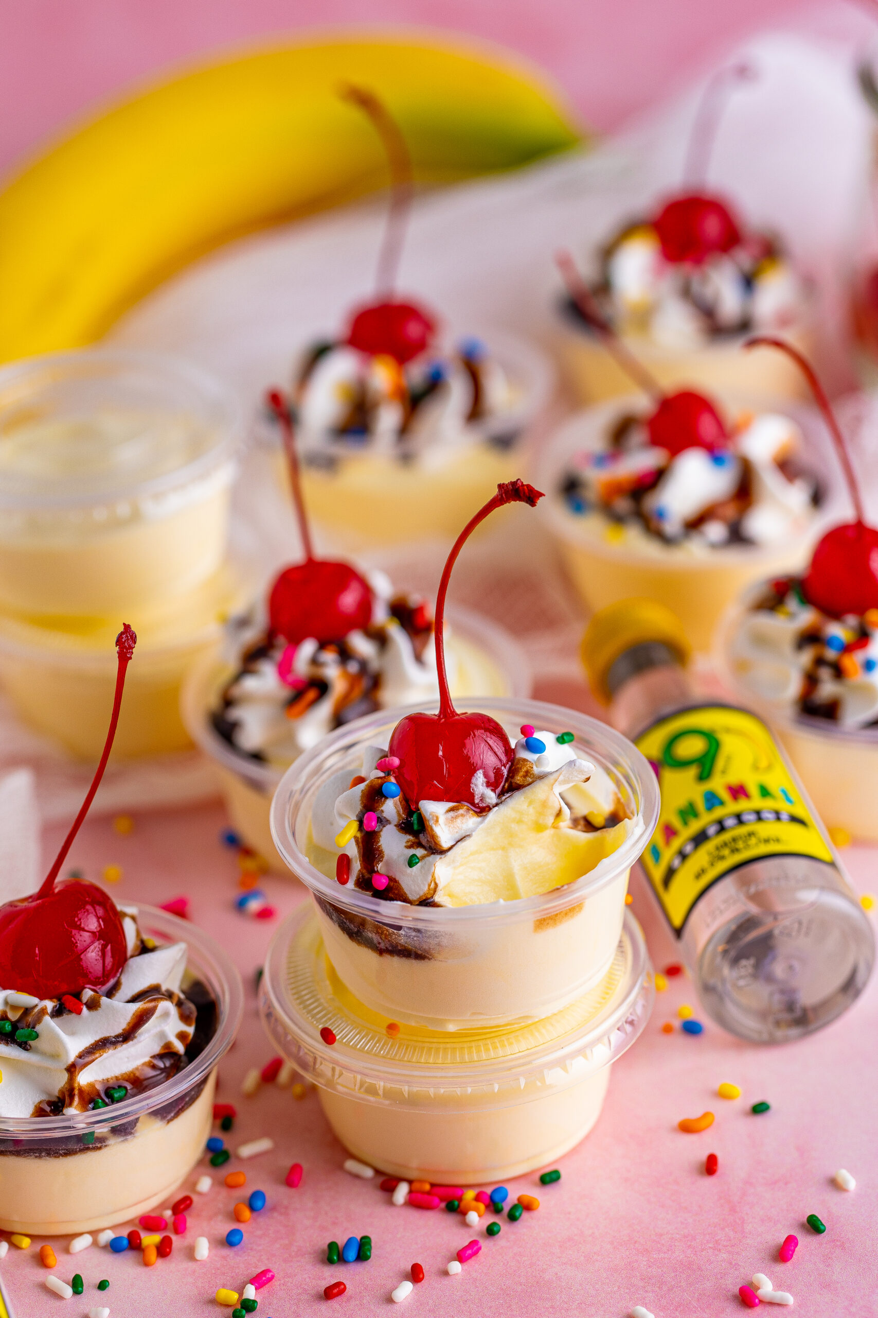 Banana pudding shots stacked surrounded by sprinkles