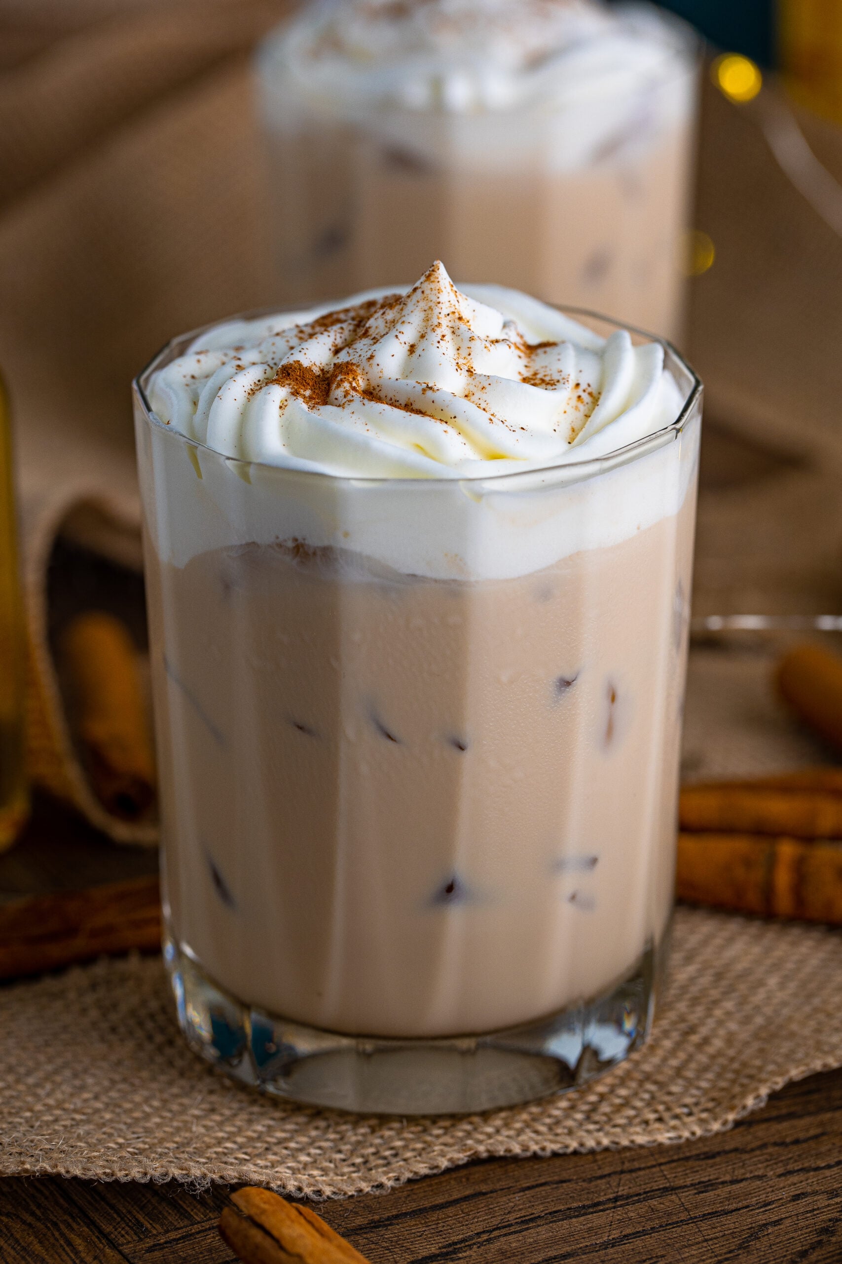 Front view of Cinnamon Roll Cocktail surrounded by cinnamon sticks.