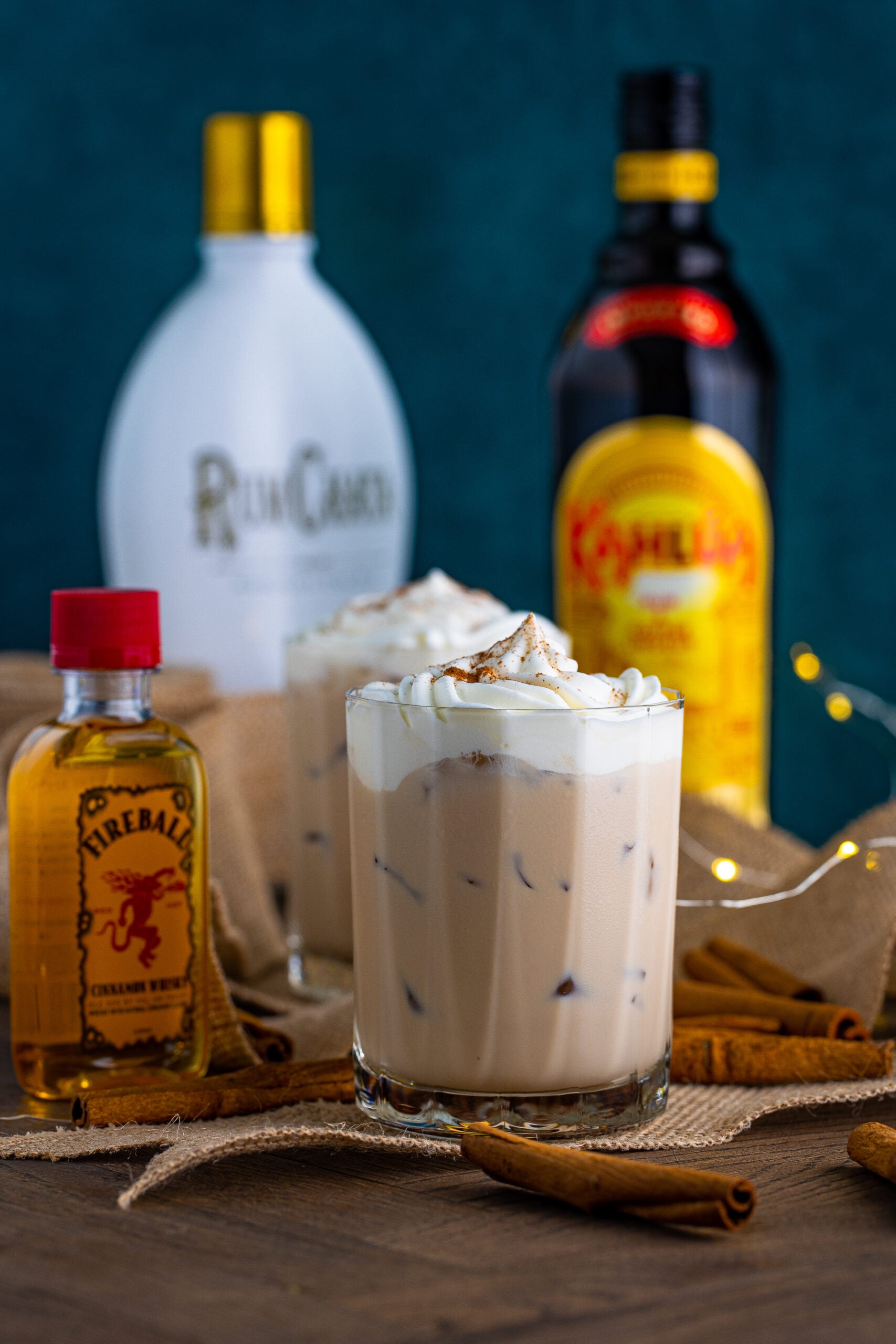 Front view of Cinnamon Roll Cocktail surrounded by cinnamon sticks.