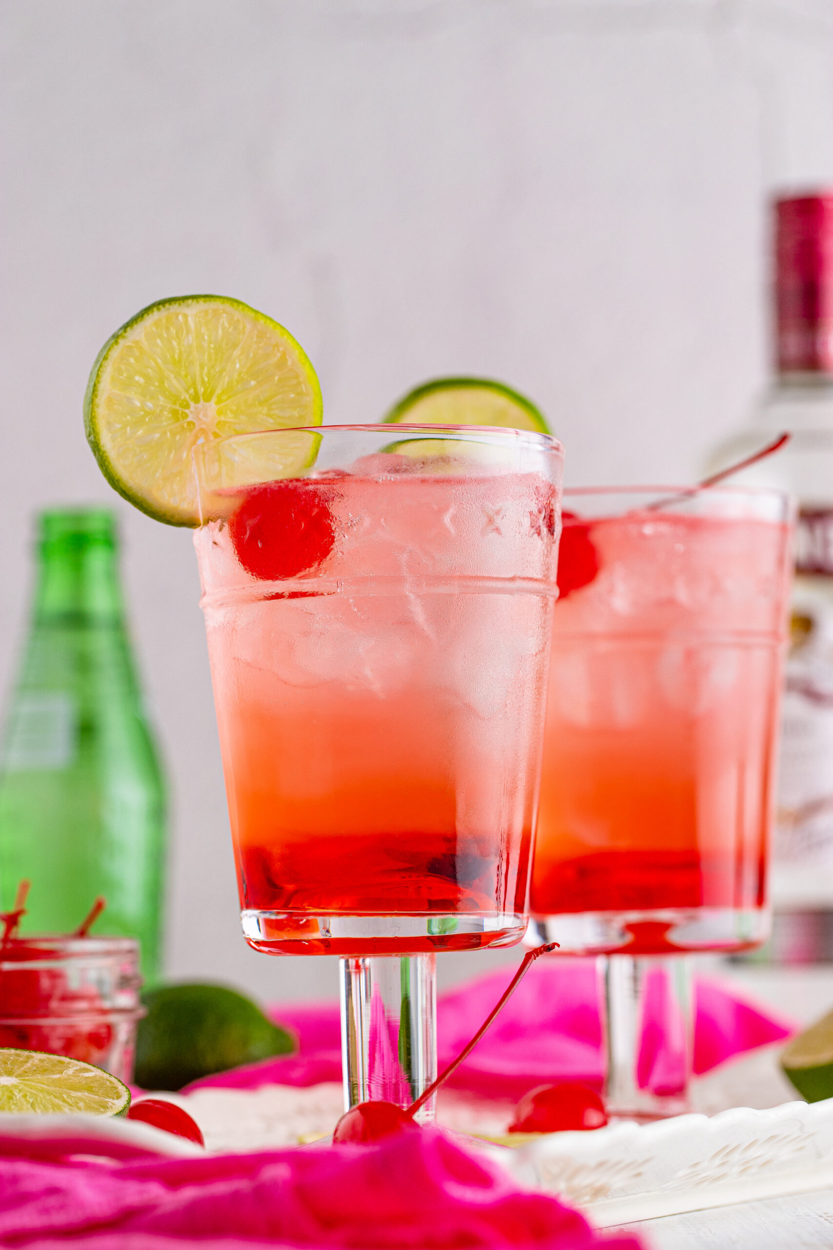 Side view of Dirty Shirley Temple garnished with a lime slice and cherry.